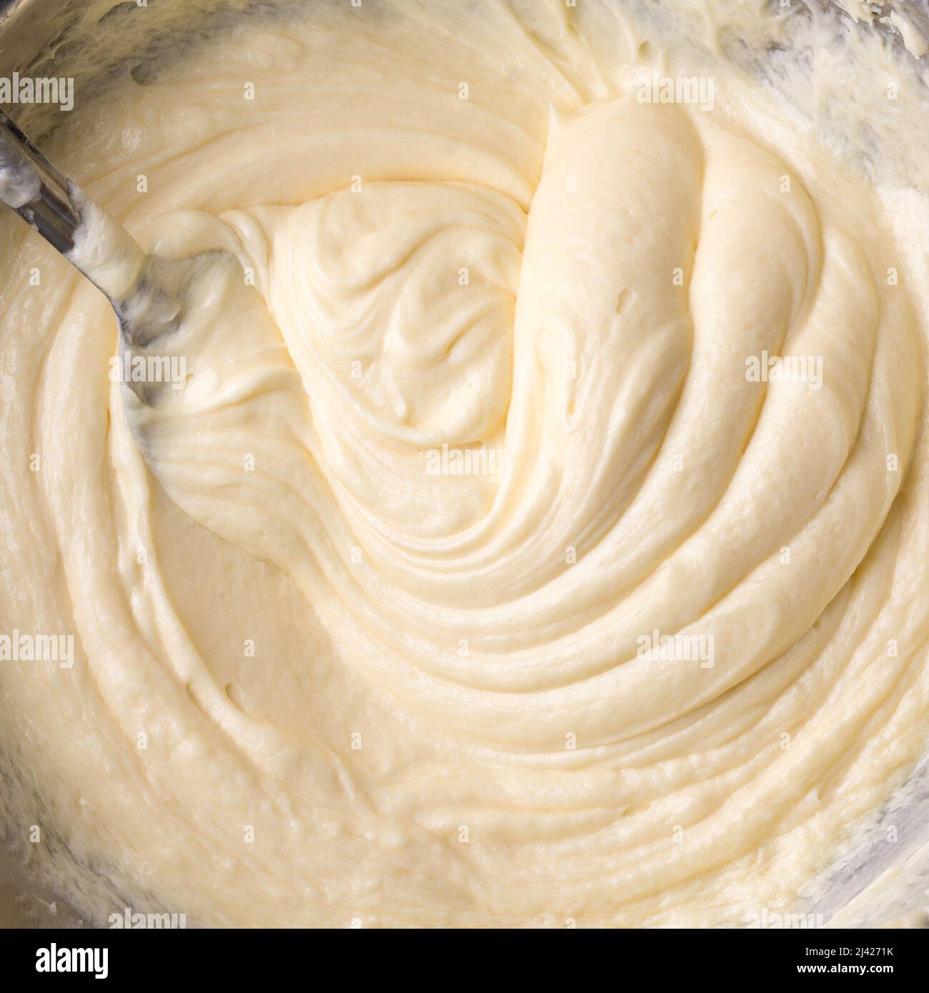 crema di burro bianca, sbattendo l'impasto con un cucchiaio, panna torta primo piano, preso dall'alto, cibo di fondo Foto Stock