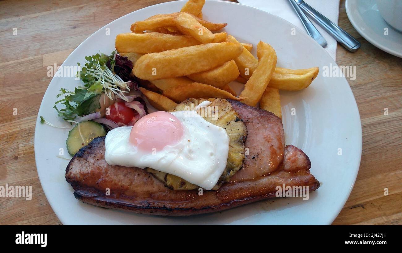 LYTHAM. LANCASHIRE. INGHILTERRA. 11-14-21. Un pasto di gammon, uova fritte e ananas servito con patatine fritte e una guarnitura di insalata. Foto Stock