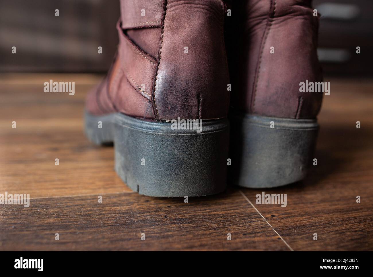 Coppia di scarpe donna in pelle marrone vestita primo piano le scarpe donna con suola nera in gomma spessa usurata si eriscono su pavimento in legno in camera con mobili Foto Stock