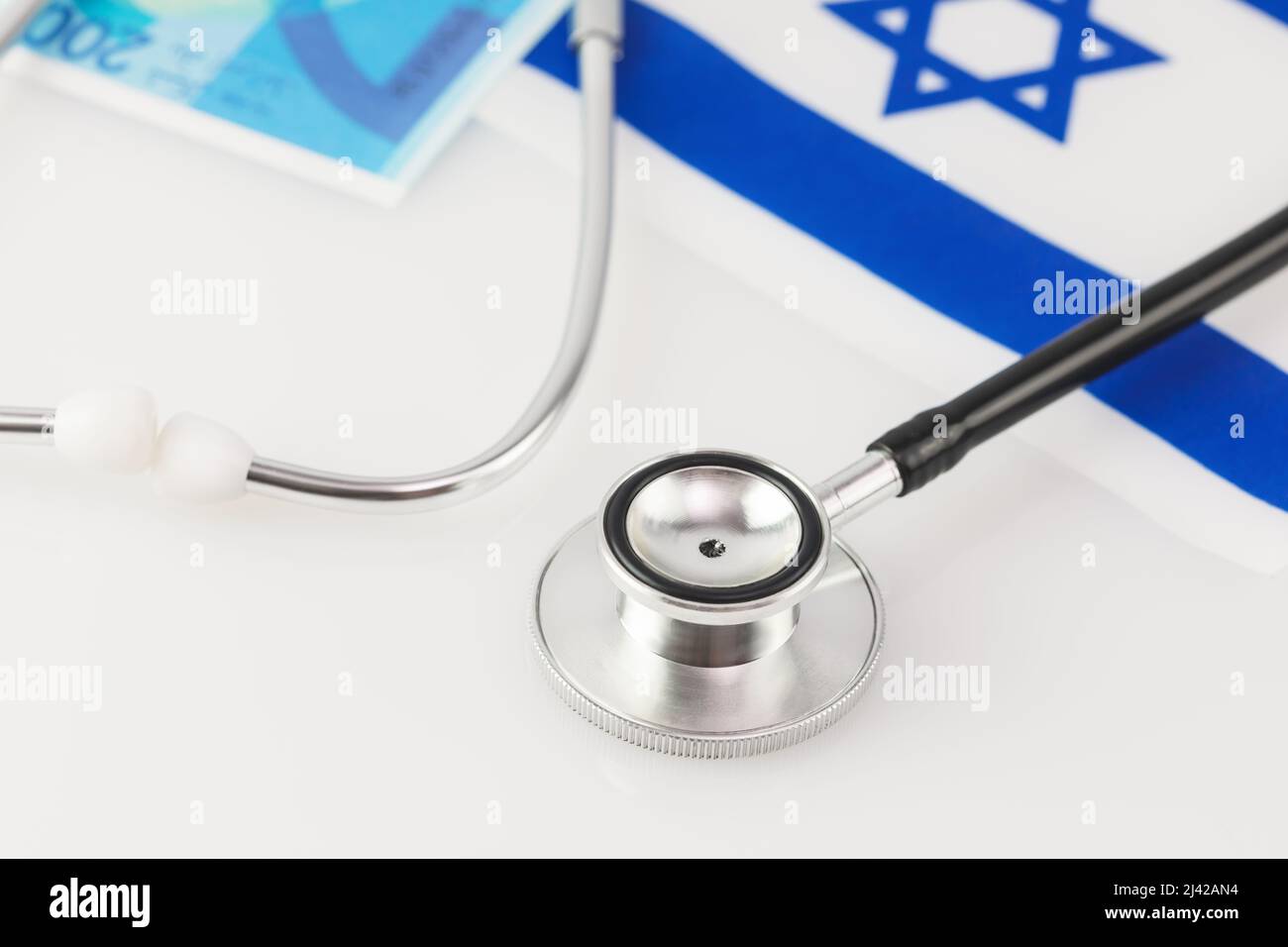 Concetto medico. Medicina privata in Israele, pagamento per trattamento. Stetoscopio, banconote Shekel e bandiera di Israele su sfondo bianco. Soft image AN Foto Stock