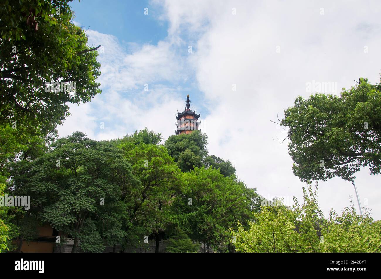 La Pagoda di Cishou sorge sopra gli alberi all'interno dell'area panoramica del tempio buddista di Jinshan nella Cina di Zhenjiang in una giornata nuvolosa nella provincia di Jiangsu. Foto Stock