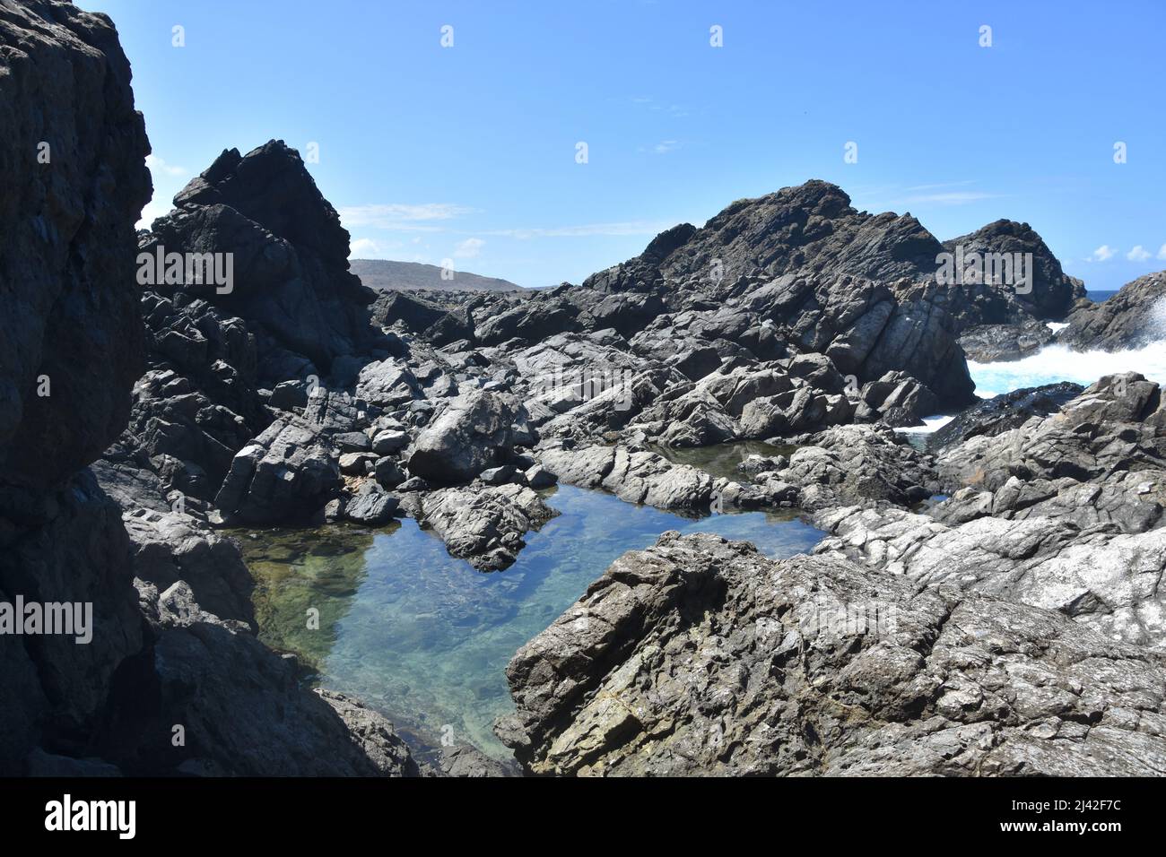 Splendida piscina naturale nascosta lungo l'aspra costa di Aruba. Foto Stock