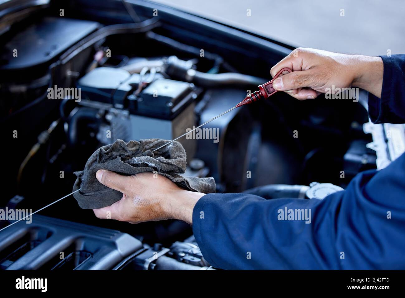 Controllo dell'olio. Colpo ad angolo alto di un meccanico maschio irriconoscibile che lavora sul motore di una vettura durante un intervento di manutenzione. Foto Stock