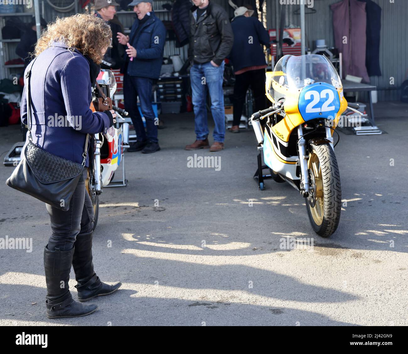 Aprile 2022 - Female fotografo che utilizza una classica telecamera TLR 120 ripresa motociclette nel paddock al Goodwood Member meeting 79. Foto Stock