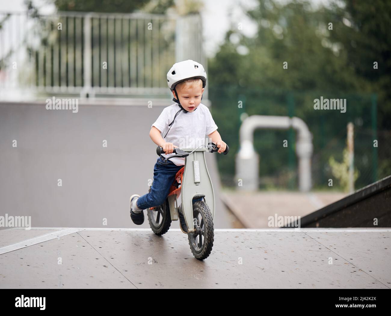Bicicletta Balance per bambini. Bambino maschio in casco imparando a correre in bicicletta al parco skate. Foto Stock