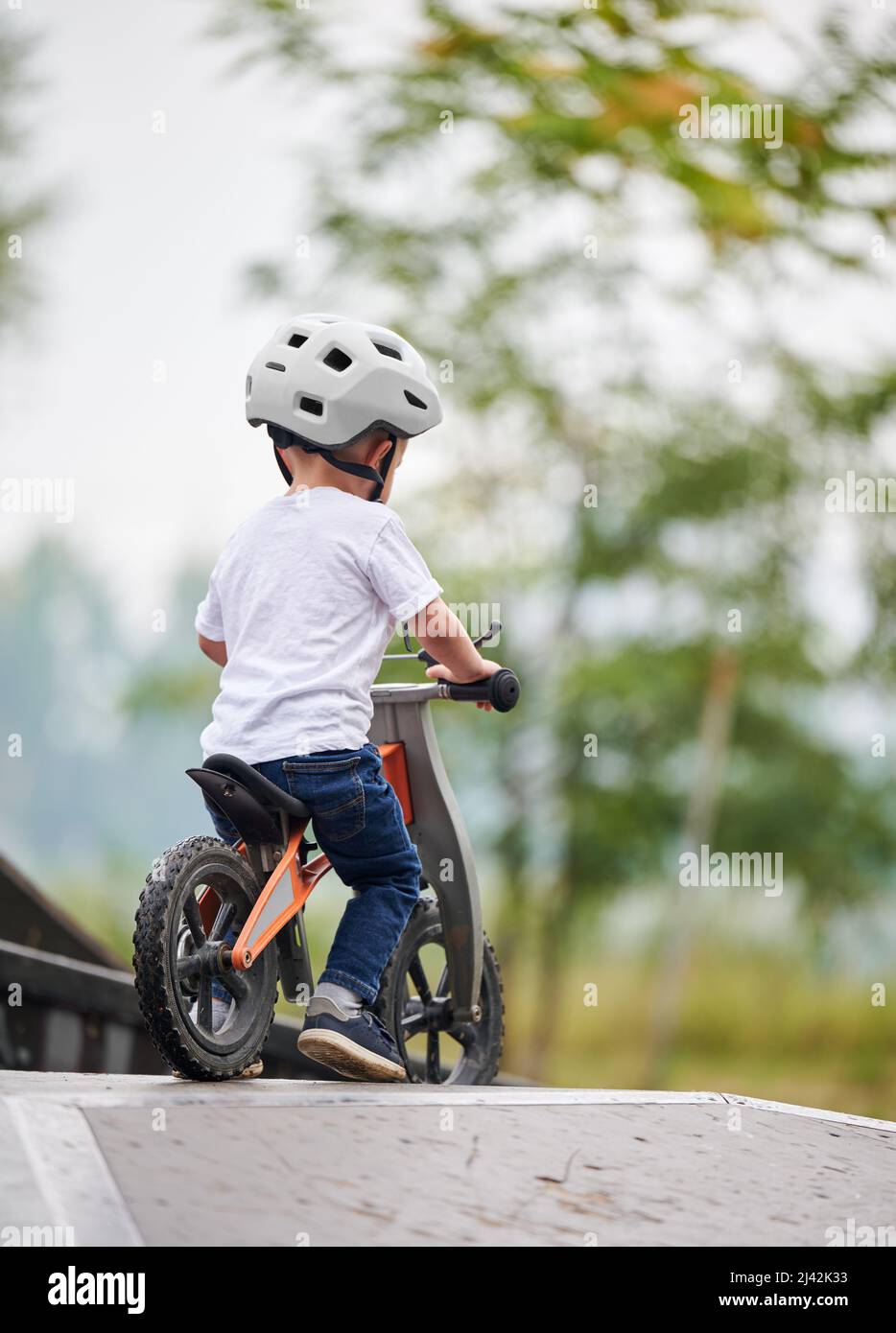 Torna indietro bicicletta per bambini con bilanciamento. Bambino maschio in casco imparando a correre in bicicletta al parco skate. Foto Stock