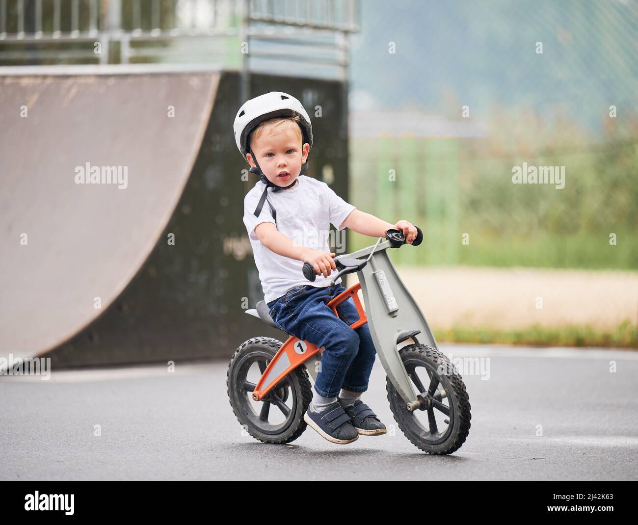 Bicicletta Balance per bambini. Bambino maschio in casco imparando a correre in bicicletta al parco skate. Foto Stock