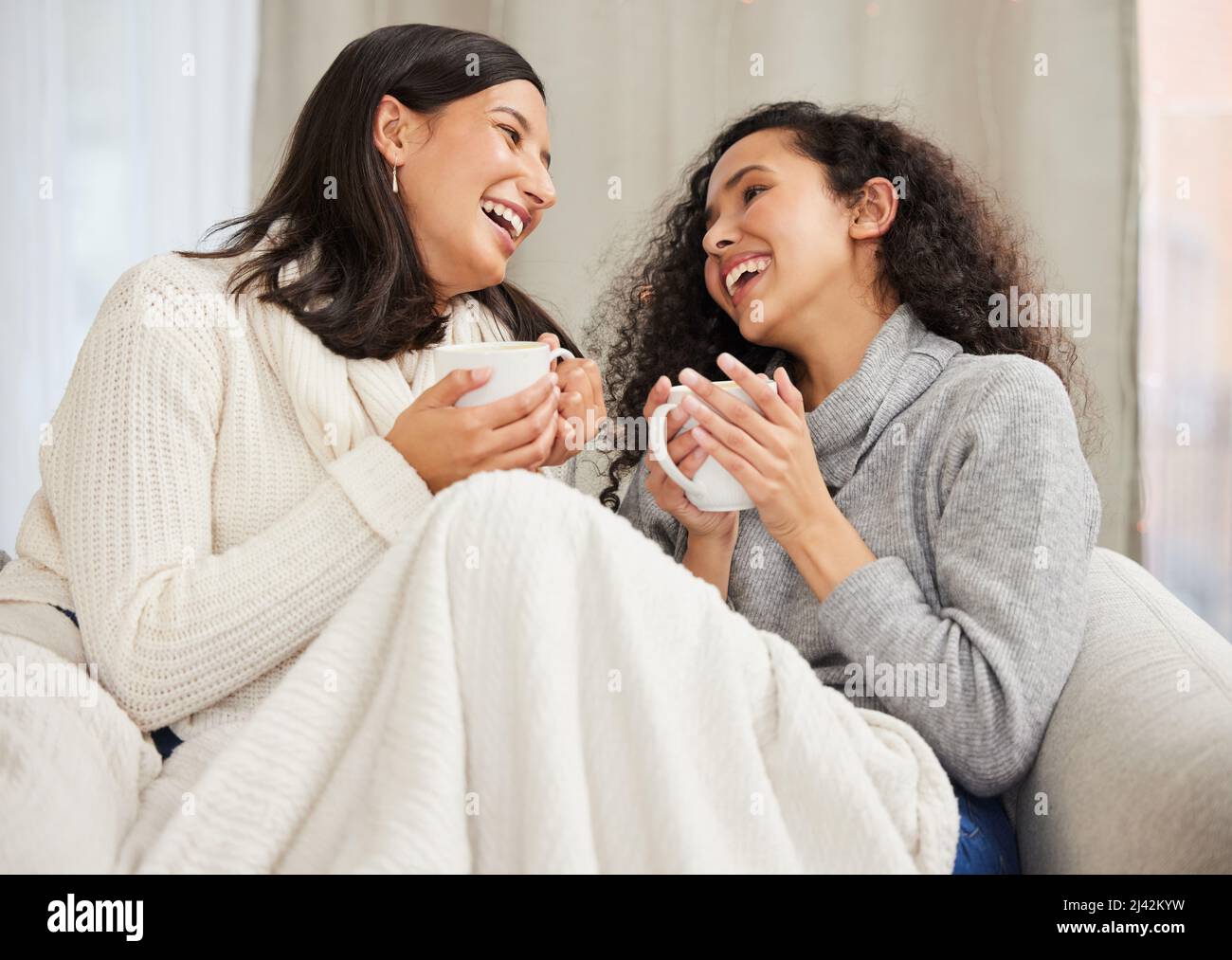 Sai solo come farmi ridere. Shot di due amici che bevono caffè e parlano a casa. Foto Stock