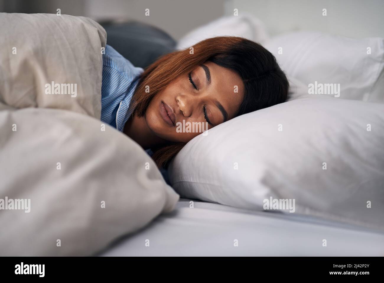 Suono addormentato. Scatto corto di una giovane donna attraente che dorme pacificamente a letto a casa. Foto Stock