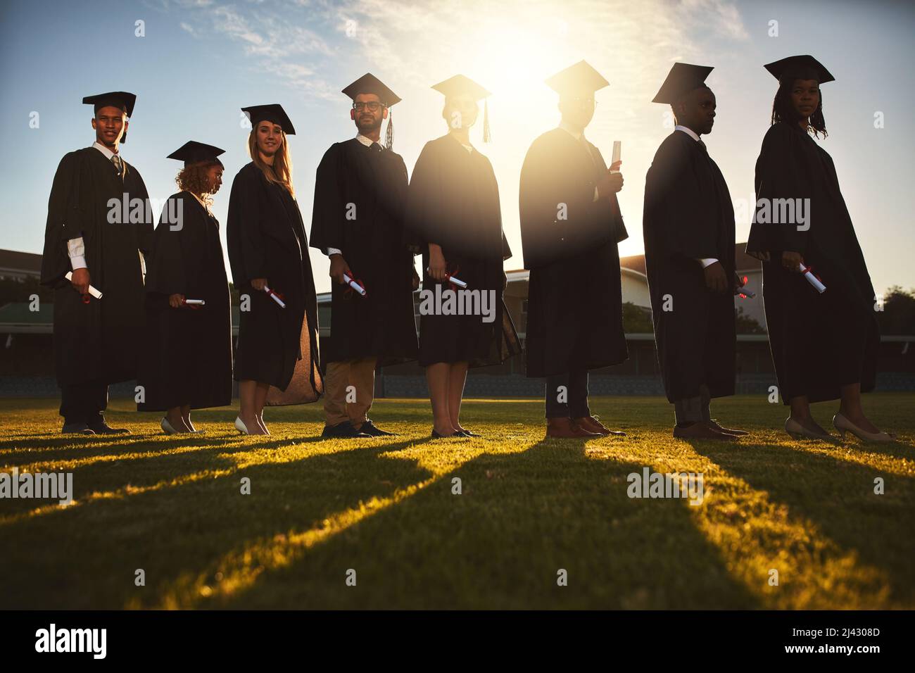 Lascia che le nuove avventure comincino. Shot di un gruppo di studenti universitari in piedi insieme il giorno della laurea. Foto Stock