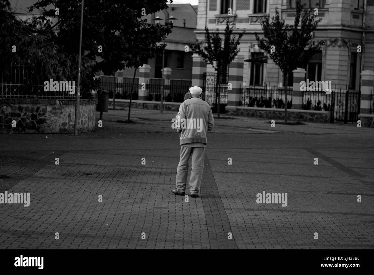 Vecchio uomo solitario che cammina attraverso la sua città natale Foto Stock