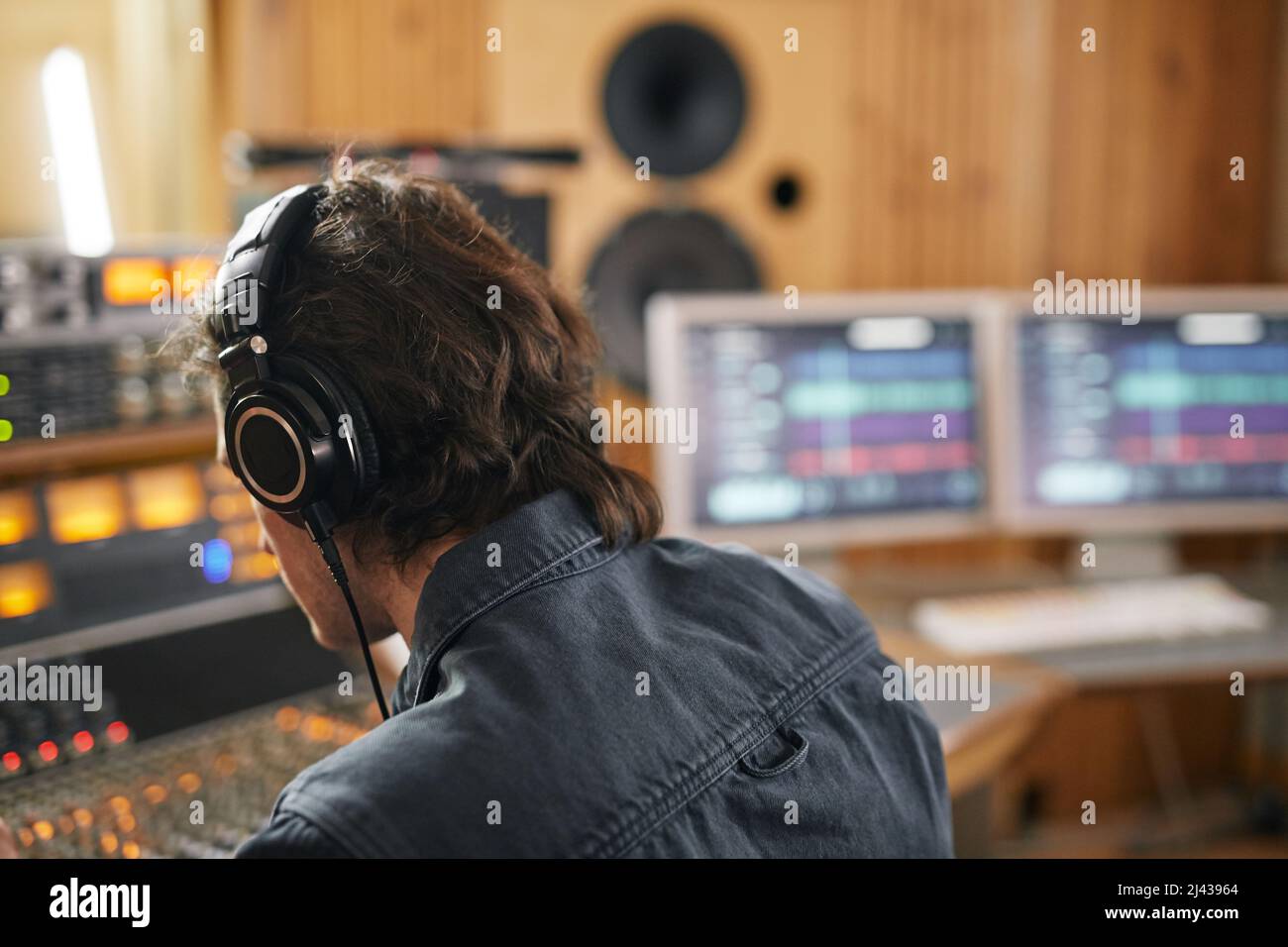 Musicista maschile che indossa le cuffie alla stazione di lavoro audio in studio di registrazione professionale, spazio copia Foto Stock