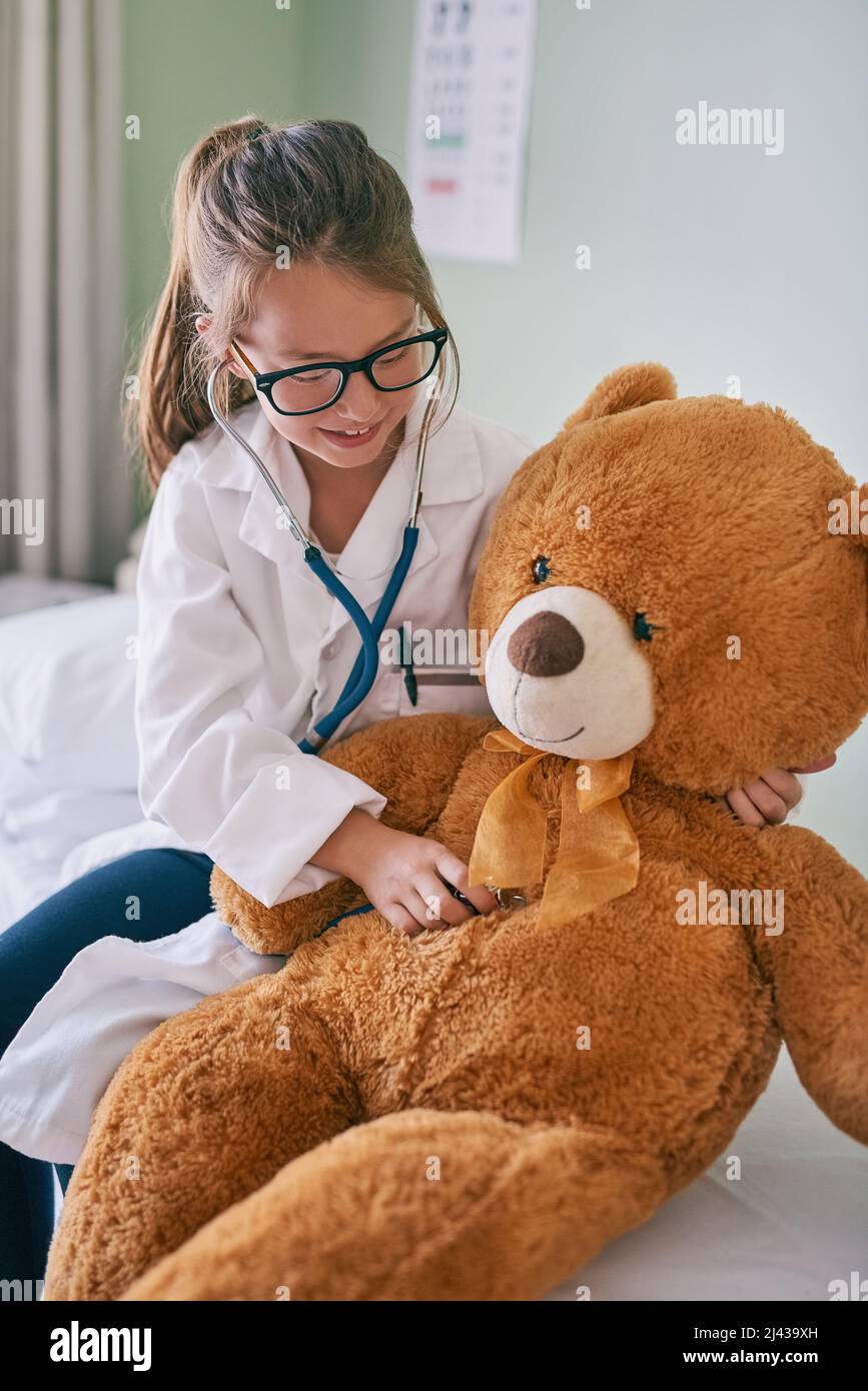 Il vostro cuore è sano e pieno di amore. Shot di una bambina che finge di essere un medico mentre esamina il suo orsacchiotto. Foto Stock
