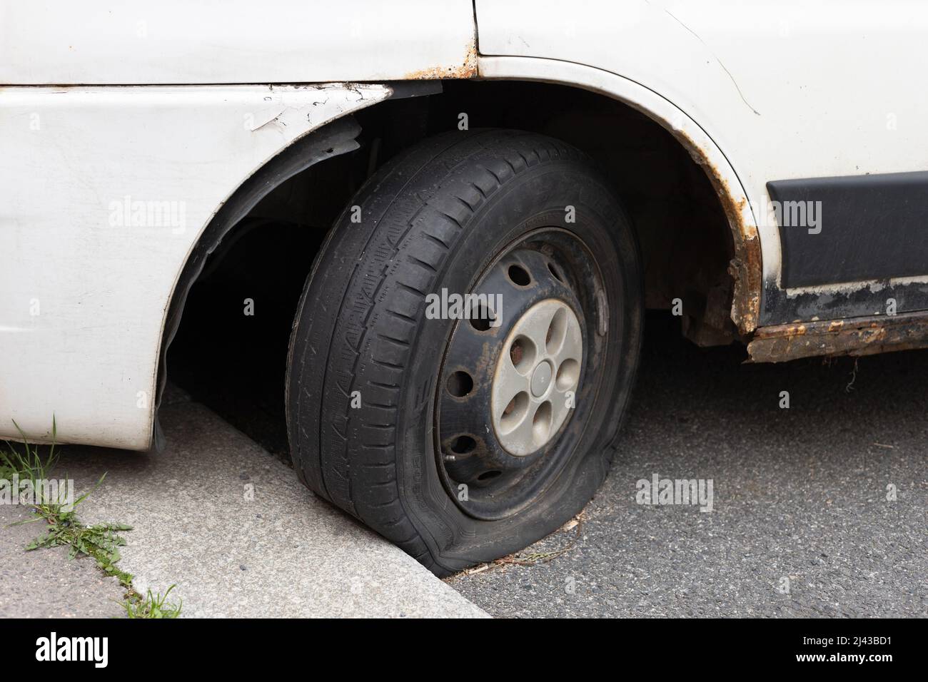 Praga, Repubblica Ceca, Czechia - 7 aprile 2022: Pneumatico e pneumatico sgonfio - ruota danneggiata e danneggiata su vecchia auto arrugginita. Messa a fuoco superficiale. Foto Stock