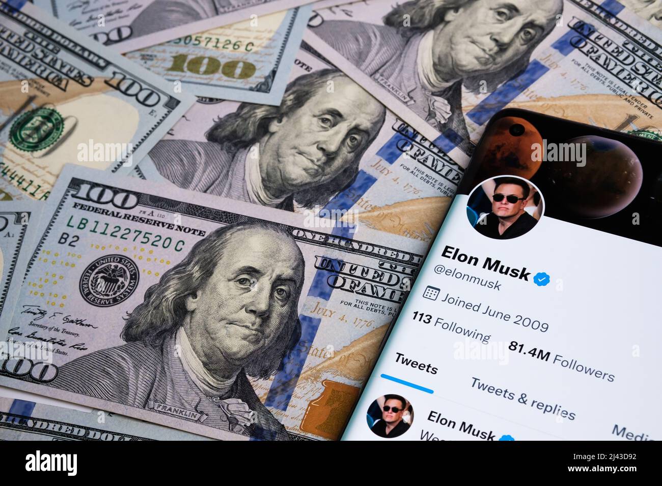 Pagina ufficiale del conto twitter di Elon Musk visualizzata sullo smartphone che è collocato sul mucchio di banconote in dollari. Concetto. Messa a fuoco selettiva. Stafford, Foto Stock