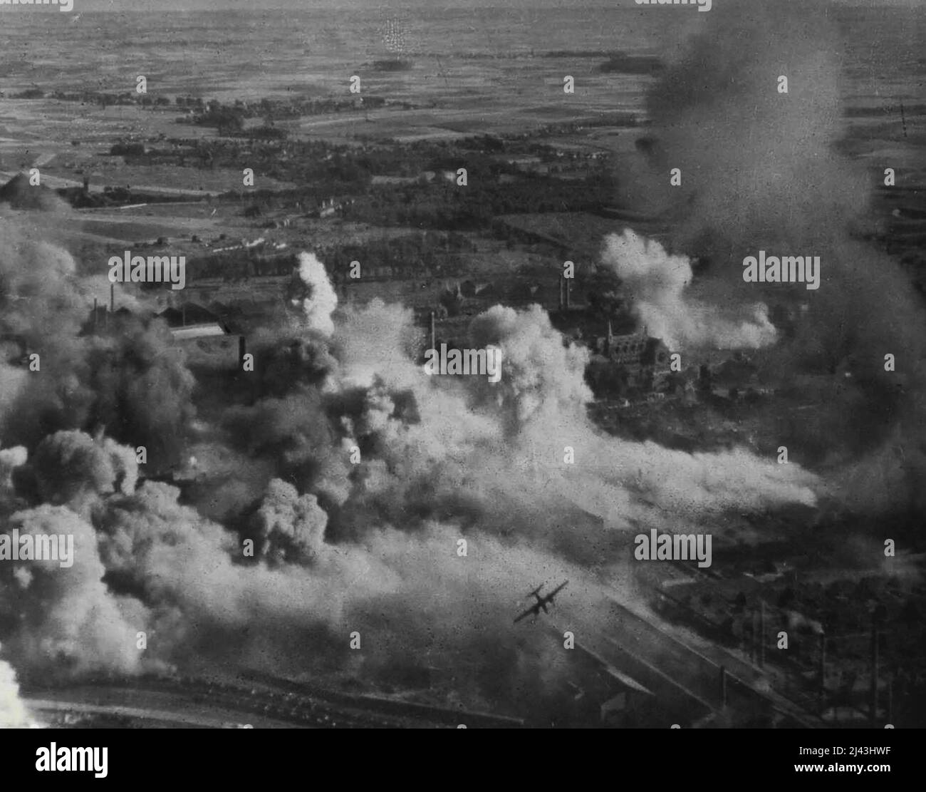 R.A.F. I Bostons attaccano i lavori d'acciaio a Denain, Francia -- un Boston (centro inferiore) è emerso dal fumo e schiuma i tetti dopo aver aggiunto il suo contributo alla distruzione nell'area bersaglio. Si noti la chiesa (centro a destra) incorniciata da fumo e bomba burst, ma apparentemente non danneggiato. Sulle fotografie ricognitolistiche non sono visibili danni a questa chiesa. Questa foto, scattata durante un attacco da Bostons di R.A.F. Comando combattente il 16,8.43., fornisce notevoli prove della precisione con cui Foto Stock