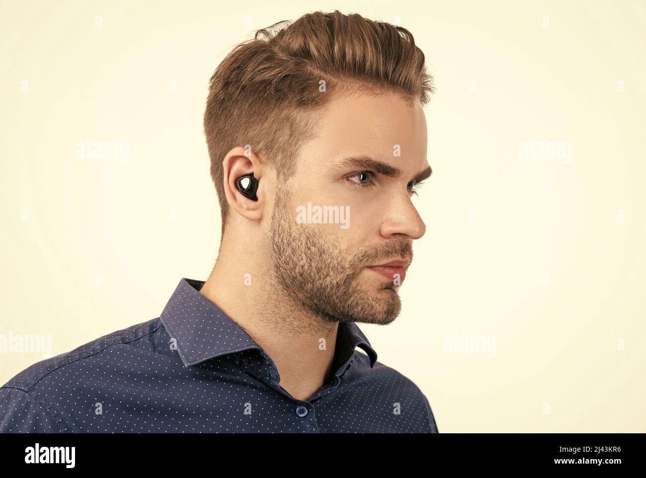 bell'uomo senza rasature con auricolari bluetooth wireless isolati sulla tecnologia bluetooth bianca Foto Stock