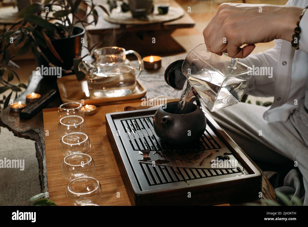 Master che serve tradizionale cerimonia del tè cinese e versare oolong da teiera con vapore su sfondo scuro Foto Stock