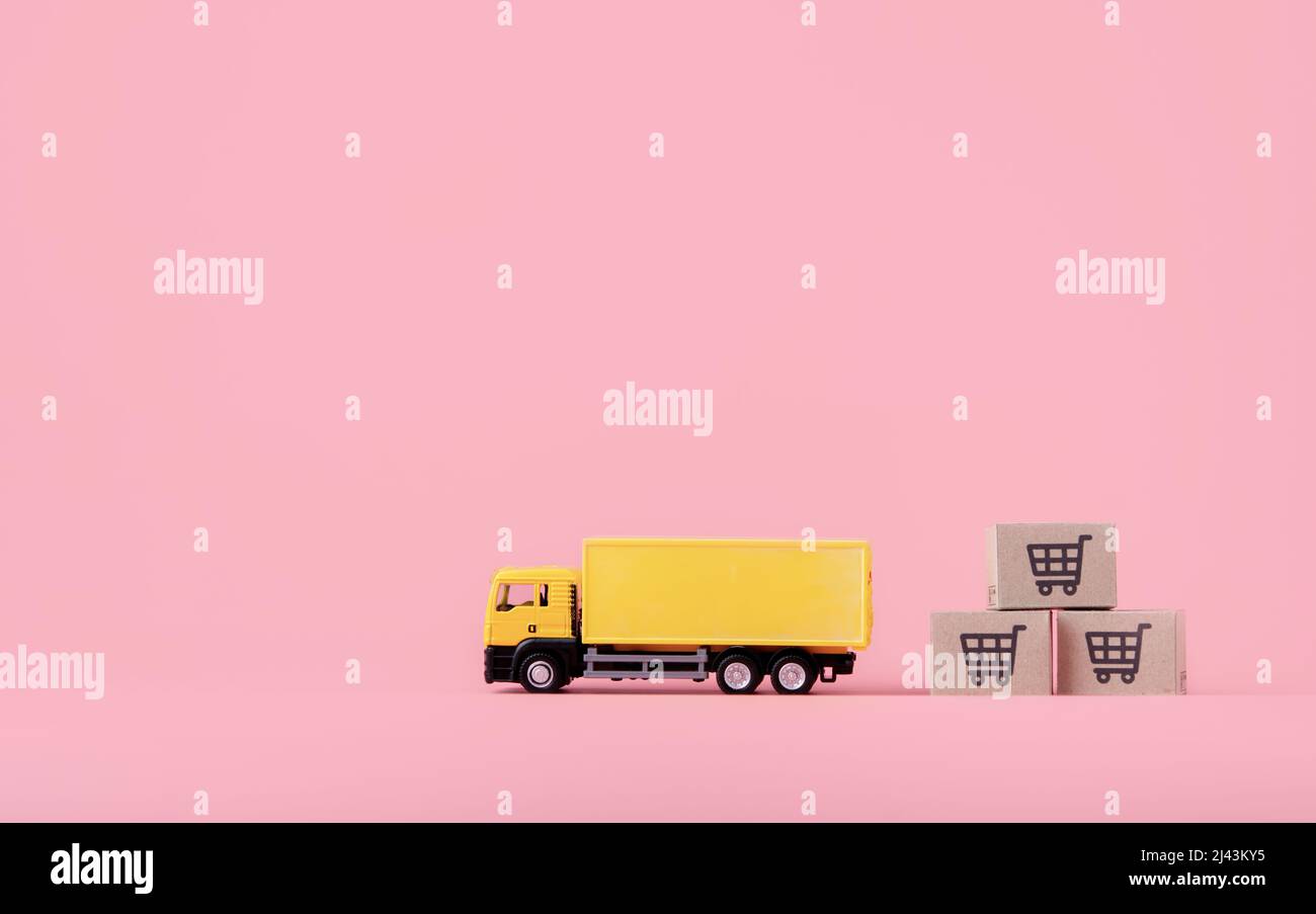 Logistica, e servizio di consegna - camion del carico e cartoni o pacchi di carta con un logo del carrello della spesa su sfondo rosa. Servizio di shopping on-line Foto Stock