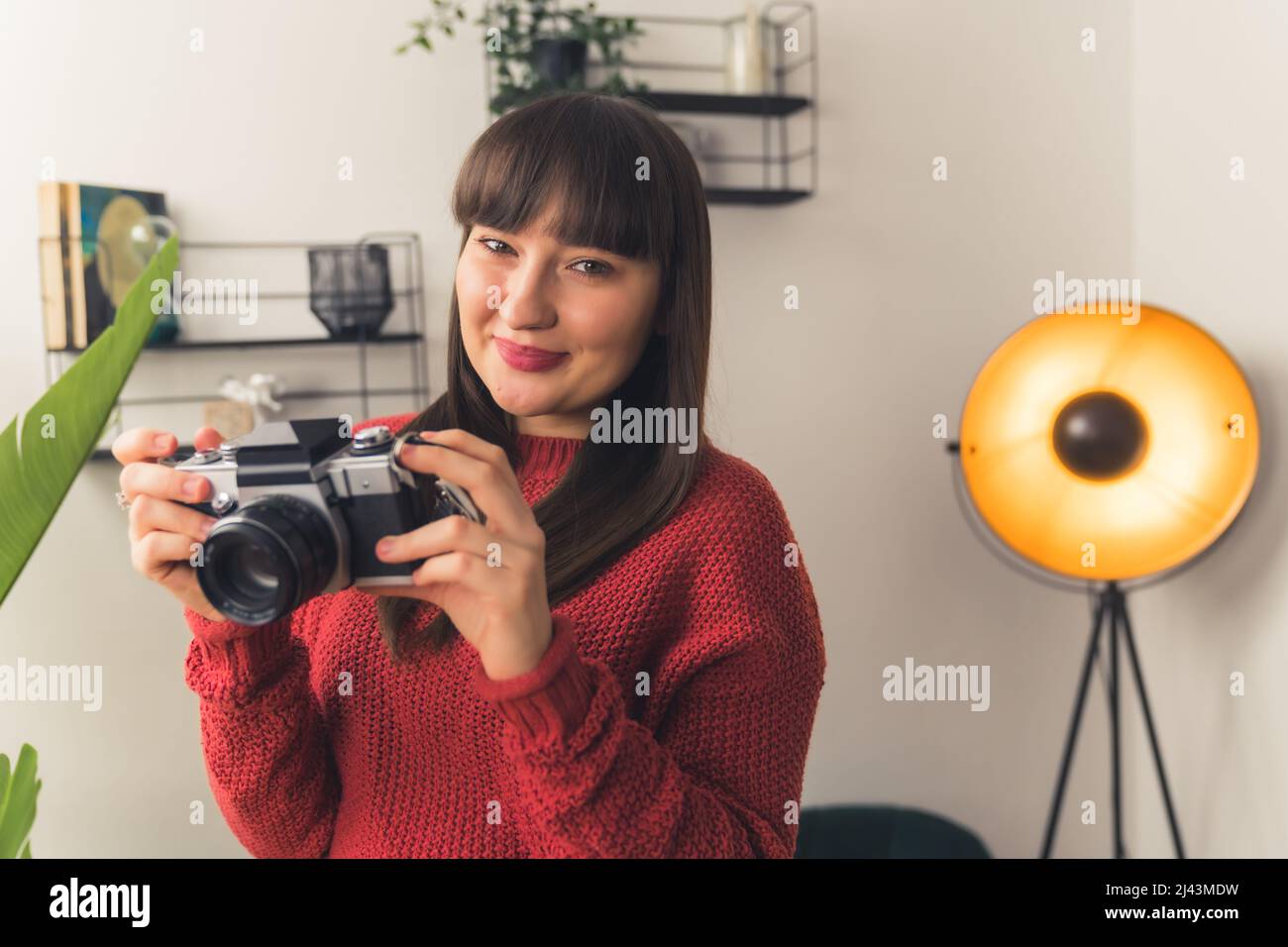 Una donna millenaria dai capelli scuri tiene la fotocamera nelle mani e sorridendo spazio per la copia del ritratto . Foto di alta qualità Foto Stock