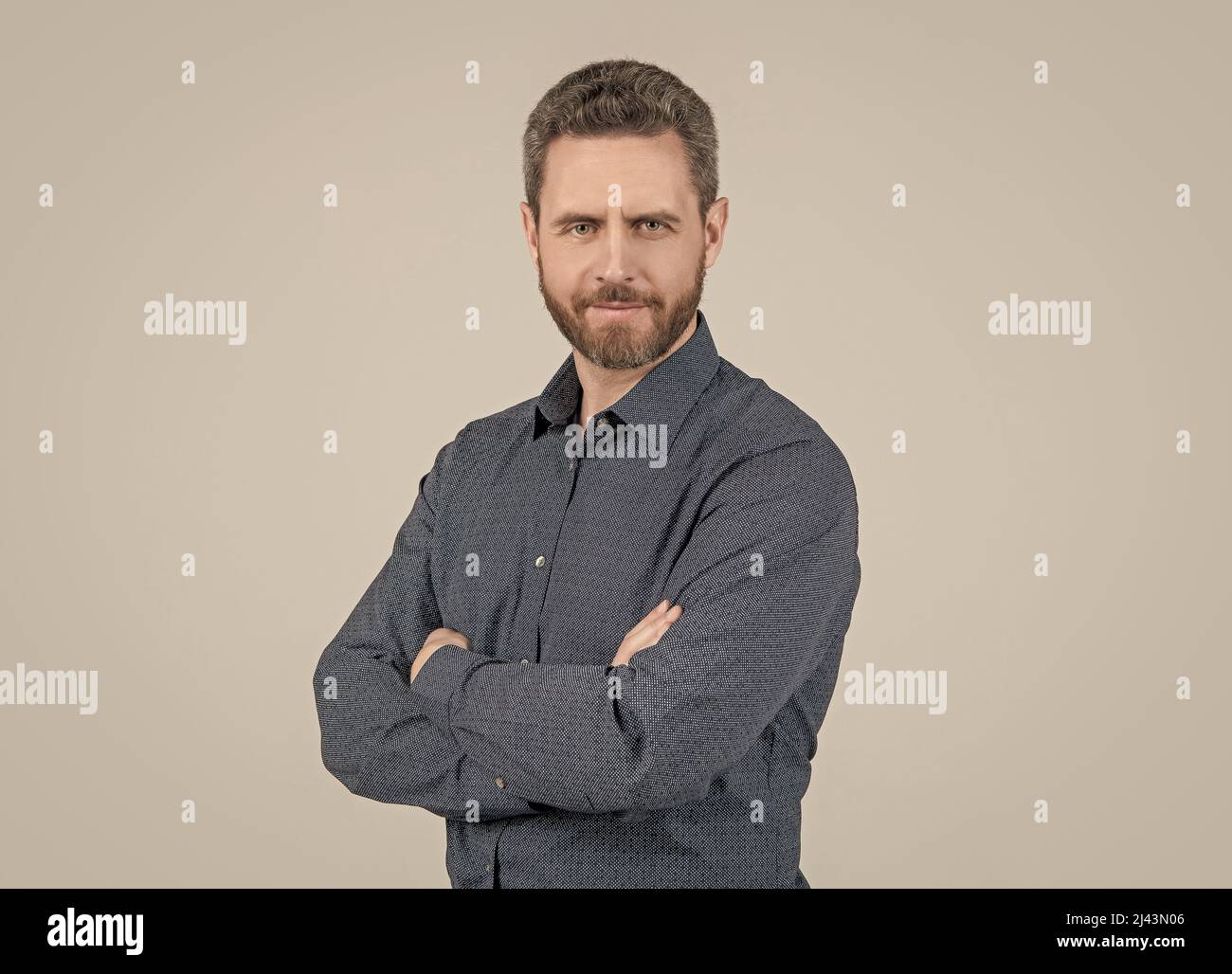 Uomo bearded in camicia casual stile mantenere le braccia incrociate sensazione di fiducia sfondo grigio, confortevole Foto Stock