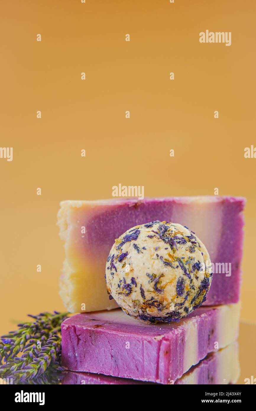 Sapone alla lavanda. Saponette e tartufi per il corpo con petali di lavanda su sfondo beige. Aromaterapia e spa con estratto di lavanda. Cosmetici Foto Stock