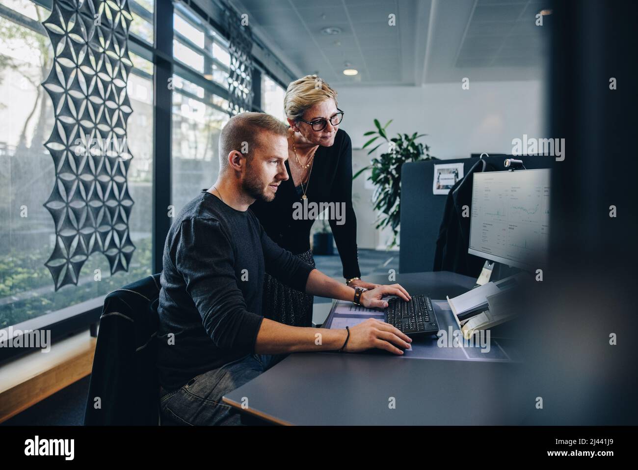 uomo d'affari che lavora su un computer con un manager in attesa. Colleghi che lavorano in ufficio. Foto Stock