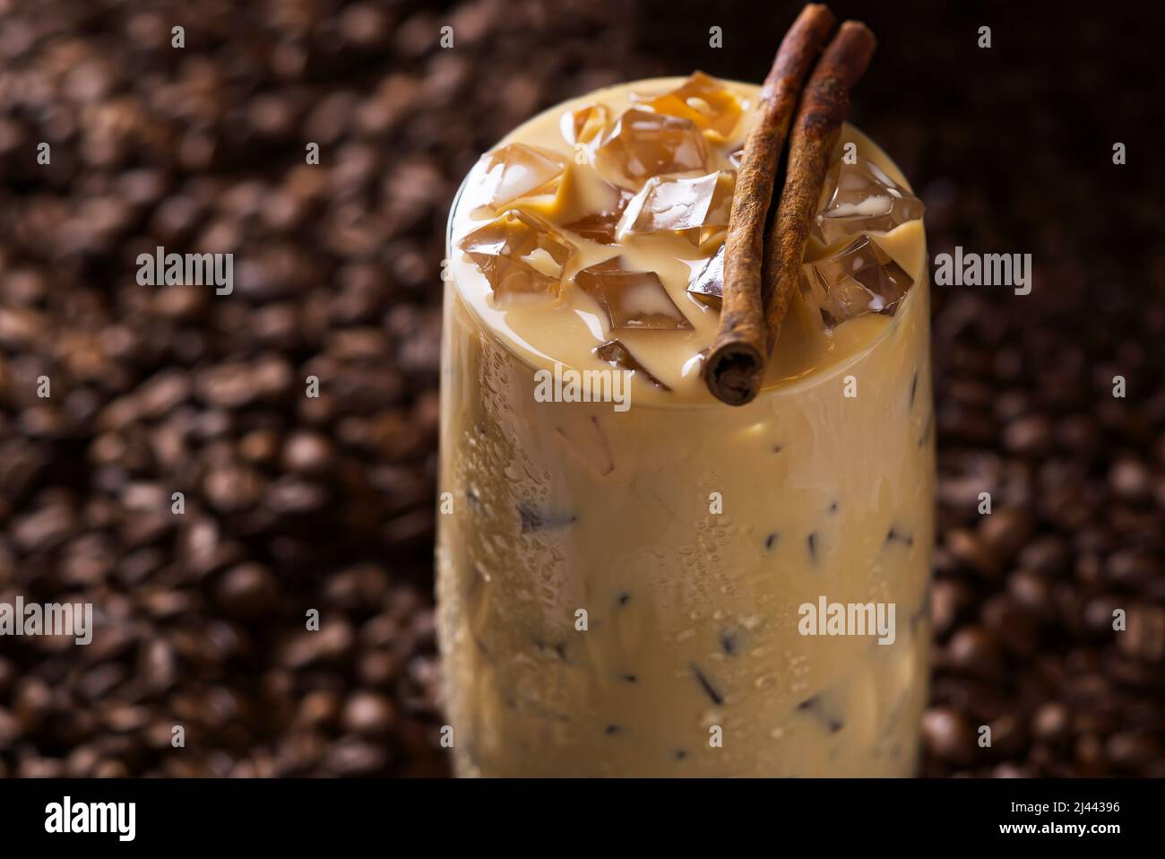 Caffè latte ghiacciato. Tazza di caffè latte ghiacciato, tè al latte su sfondo di semi di caffè scuri Foto Stock