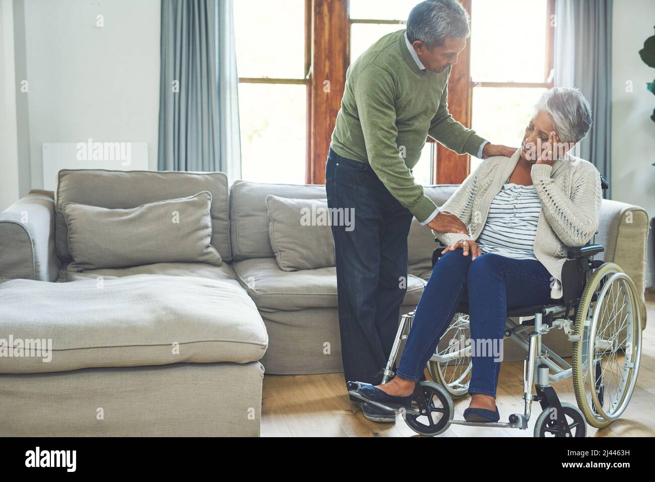 Lo faremo insieme. Shot di una donna anziana preoccupata, seduta su una sedia a rotelle, mentre è sostenuta e tenuta dal marito all'interno Foto Stock