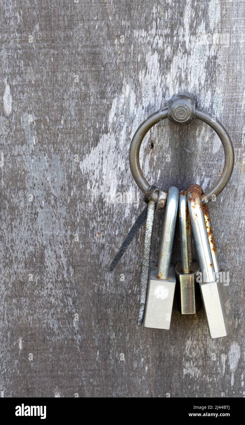 Mazzo di vecchie serrature e chiavi appese su porta in legno anello maniglia in ottone Foto Stock