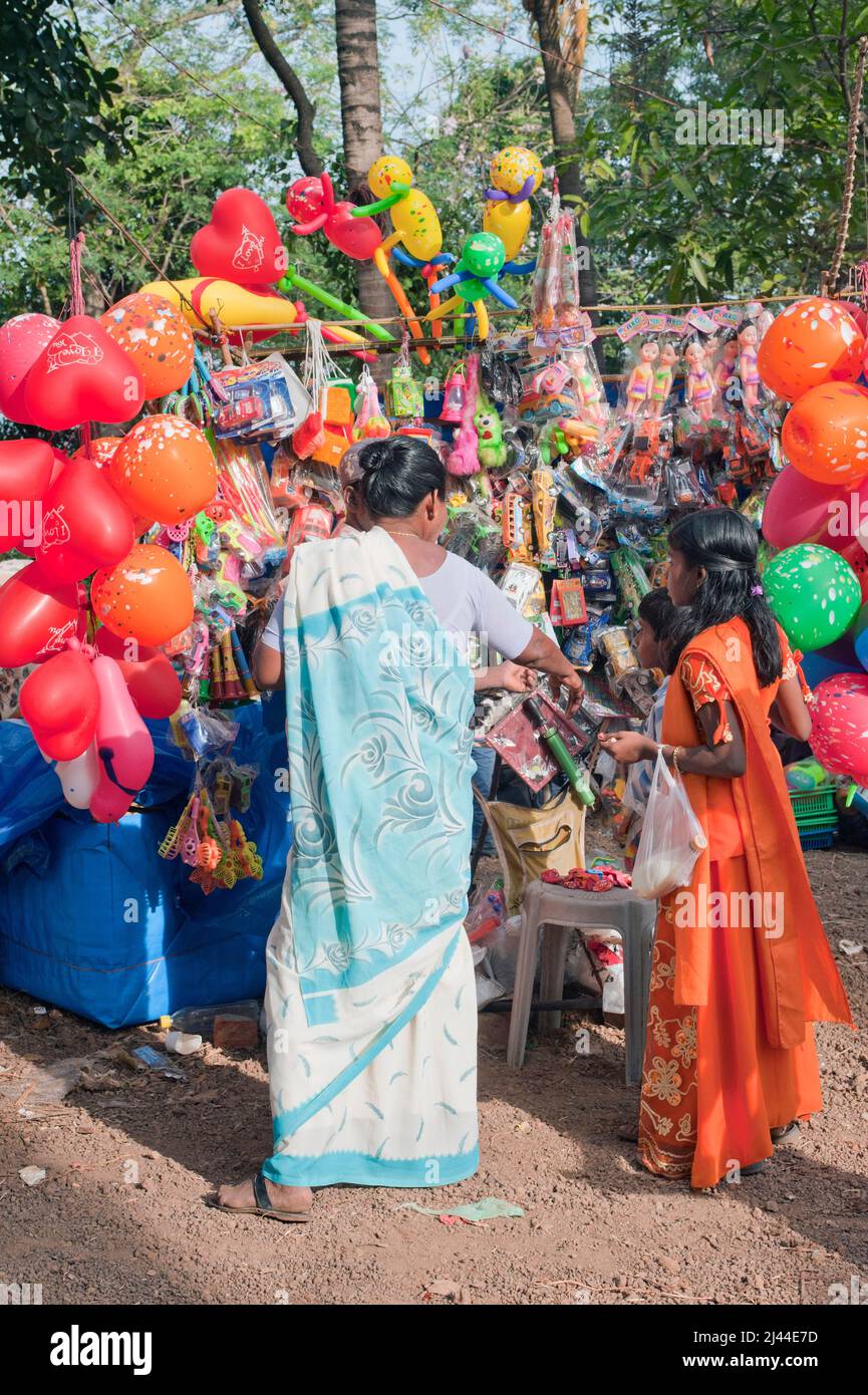 Donna che baying giocattoli colorati per i suoi figli dal venditore in Thaipusam Festival in stato Kerala India Foto Stock