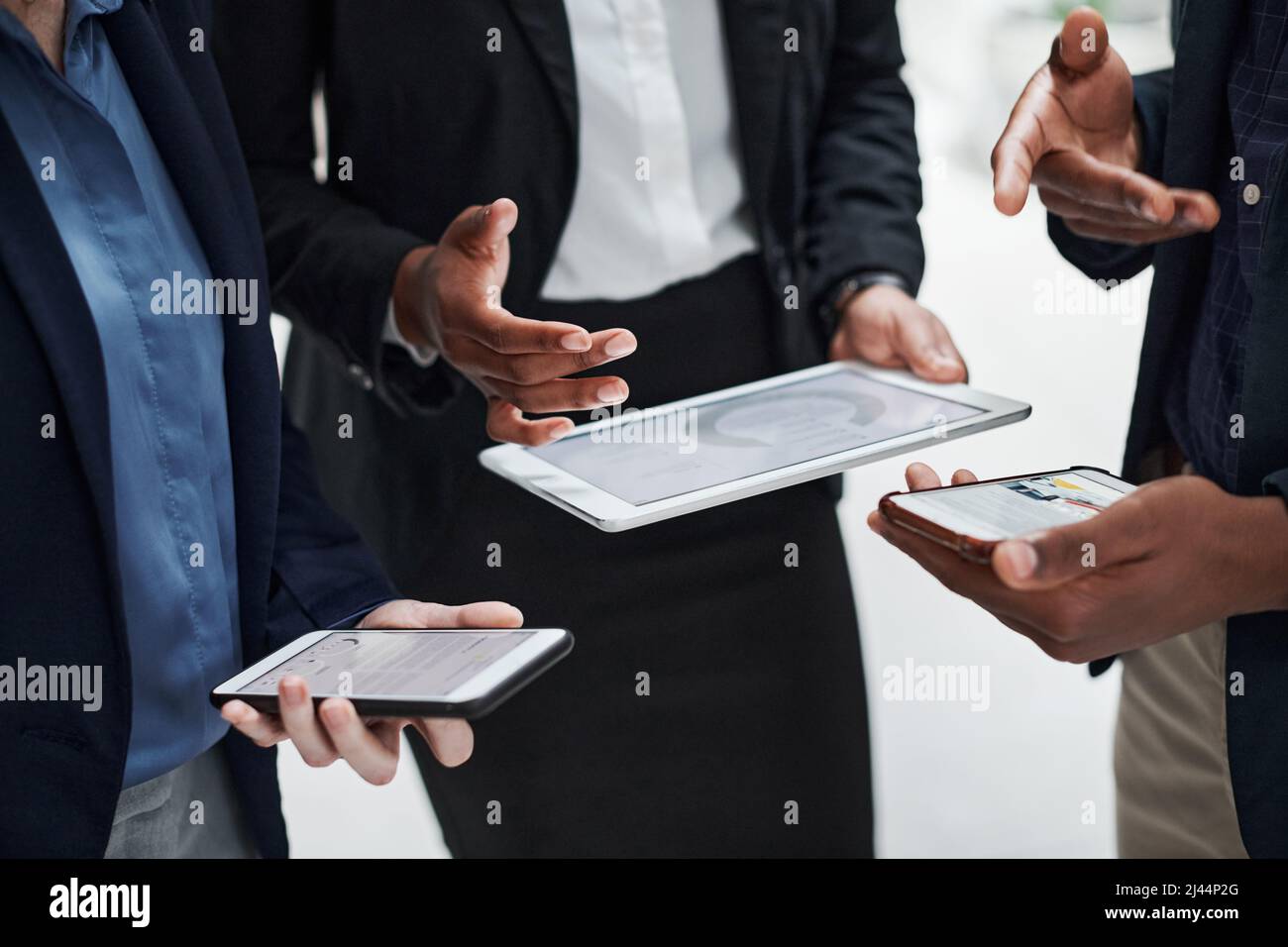 Elaborazione dei dati meno la carta. Foto di un gruppo di uomini d'affari che utilizzano dispositivi wireless durante una riunione in un ufficio moderno. Foto Stock