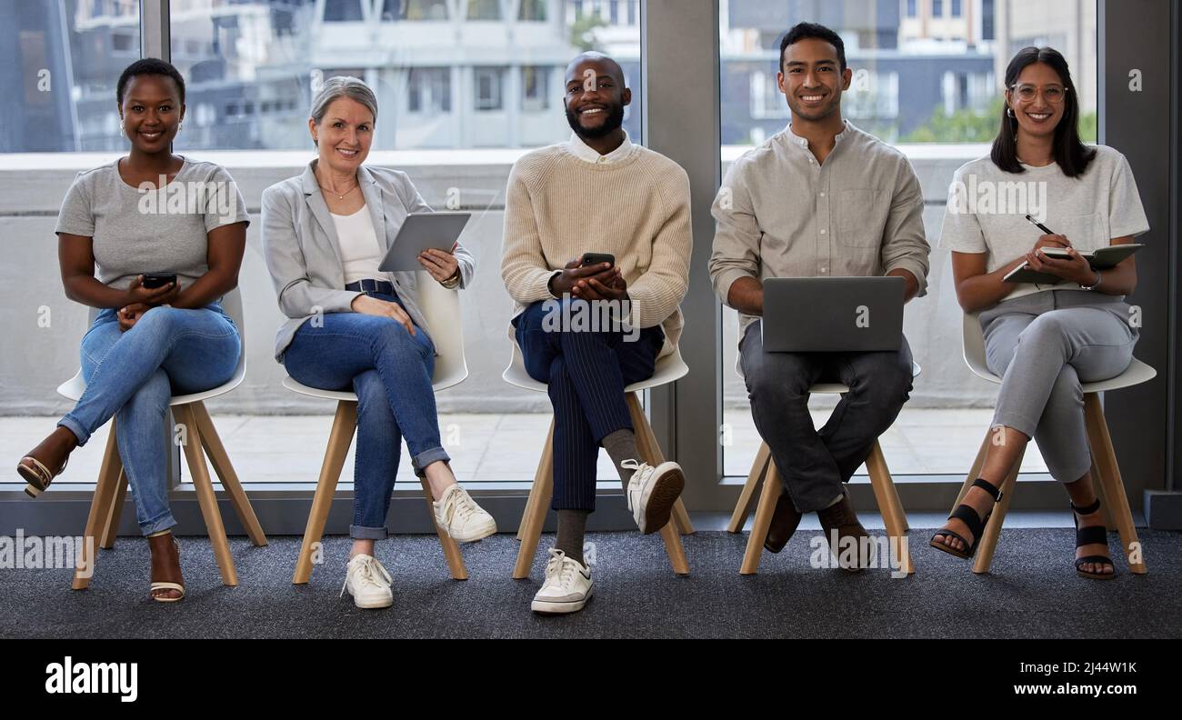 Che cosa portate al tavolo. Scatto di un gruppo di uomini d'affari che utilizzano dispositivi wireless in attesa di un colloquio. Foto Stock
