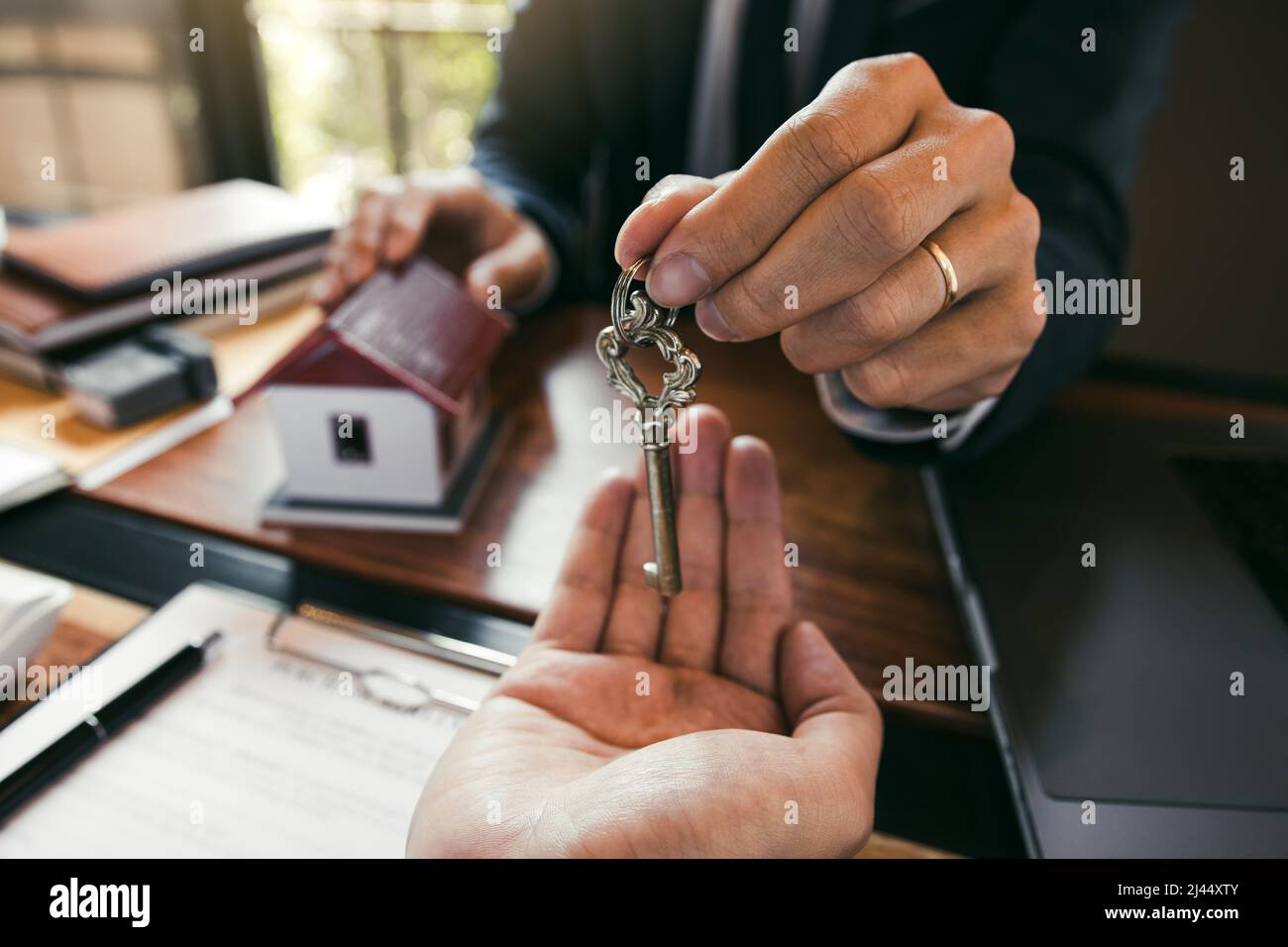 I mediatori della casa del venditore forniscono la chiave ai nuovi proprietari di abitazione in ufficio. Foto Stock