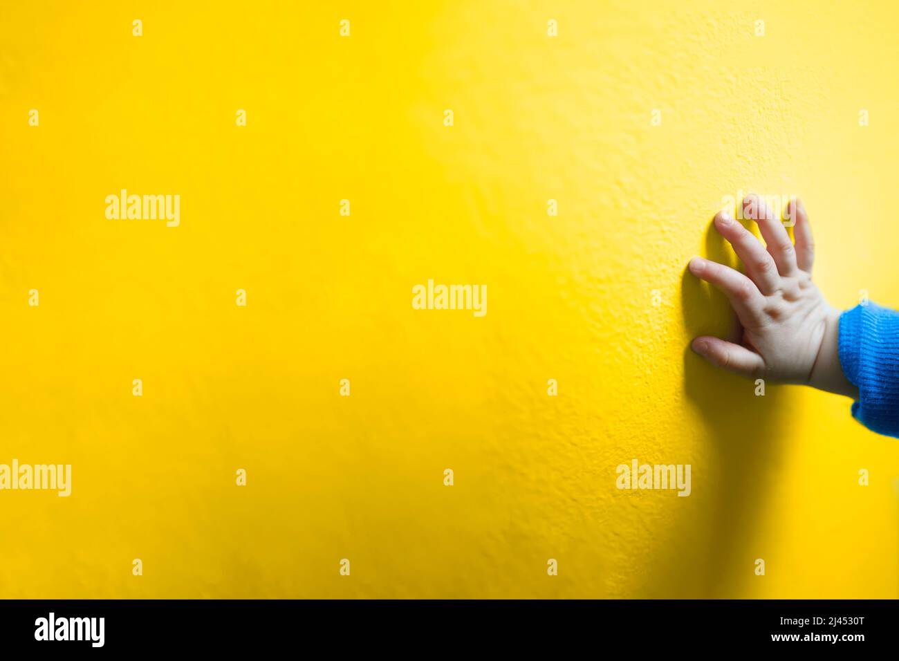 Bambino mano su un fondo giallo semplice-i rifugiati Ucraina aiuto concetto Foto Stock