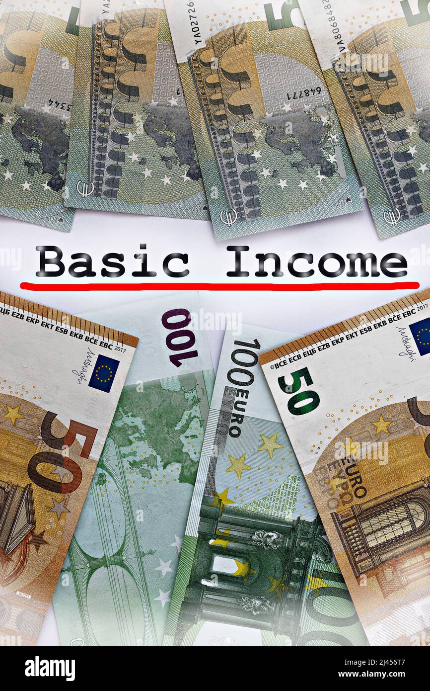 Concetto verticale del tema reddito di base universale. Le parole reddito di base su carta, circondato da dollari e bollette in euro Foto Stock