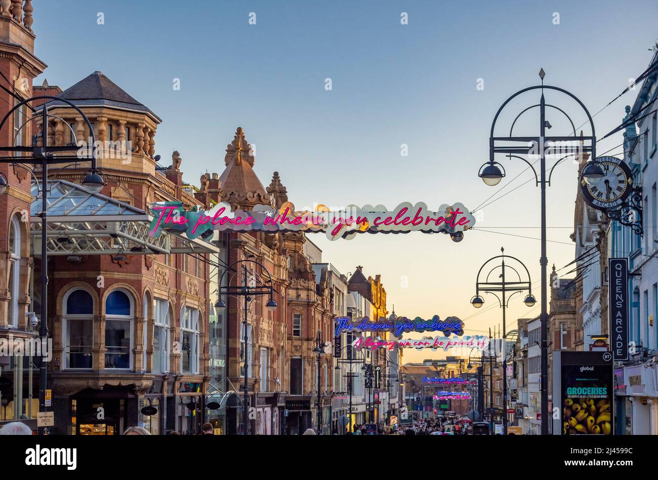 Segnali al neon illuminati sospesi a Briggate, al crepuscolo. Leeds, Regno Unito Foto Stock