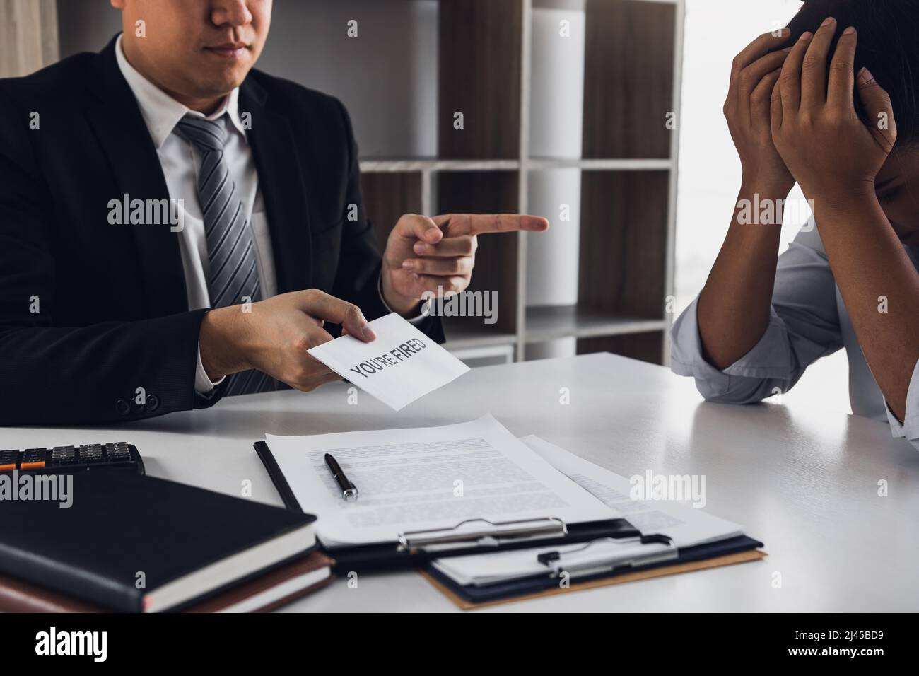 Il manager maschile ha consegnato il certificato di licenziamento al dipendente maschile mentre firma il contratto per uscire o dimettersi. Foto Stock