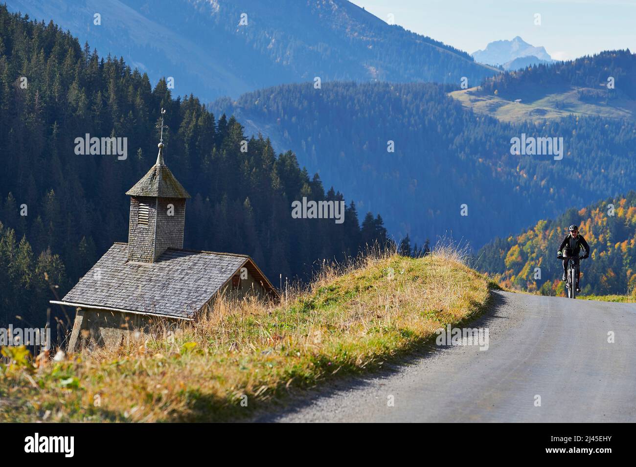 Le Grand-Bornand (Alpi francesi, Francia centro-orientale): Ciclista sulla strada che porta al passo “col des Annes” e la cappella “chapelle de la Duche” *** Foto Stock