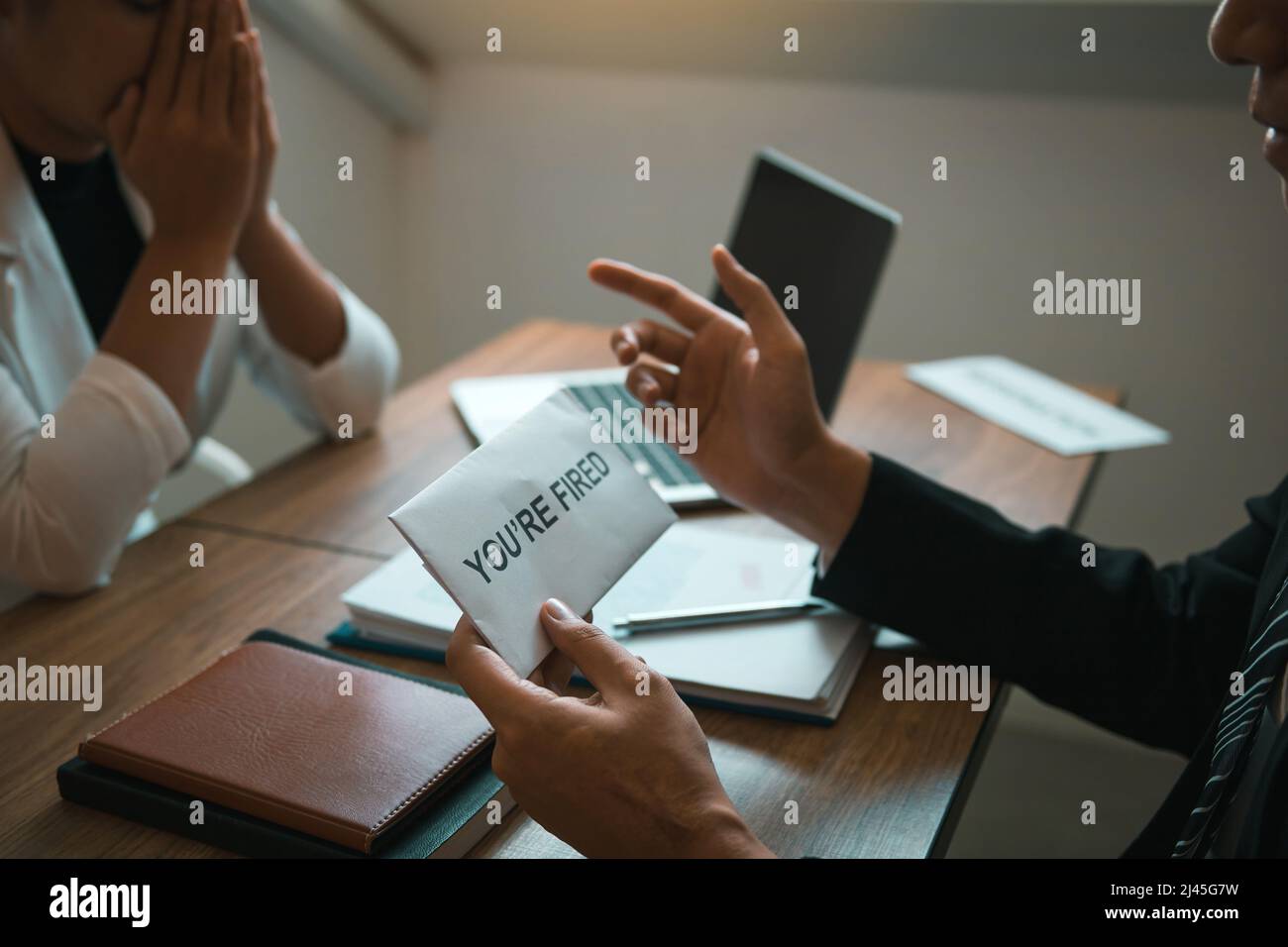 Il manager maschile sta parlando o spiegando di dover licenziare il dipendente mentre viene consegnata una busta di dimissioni al dipendente. Foto Stock