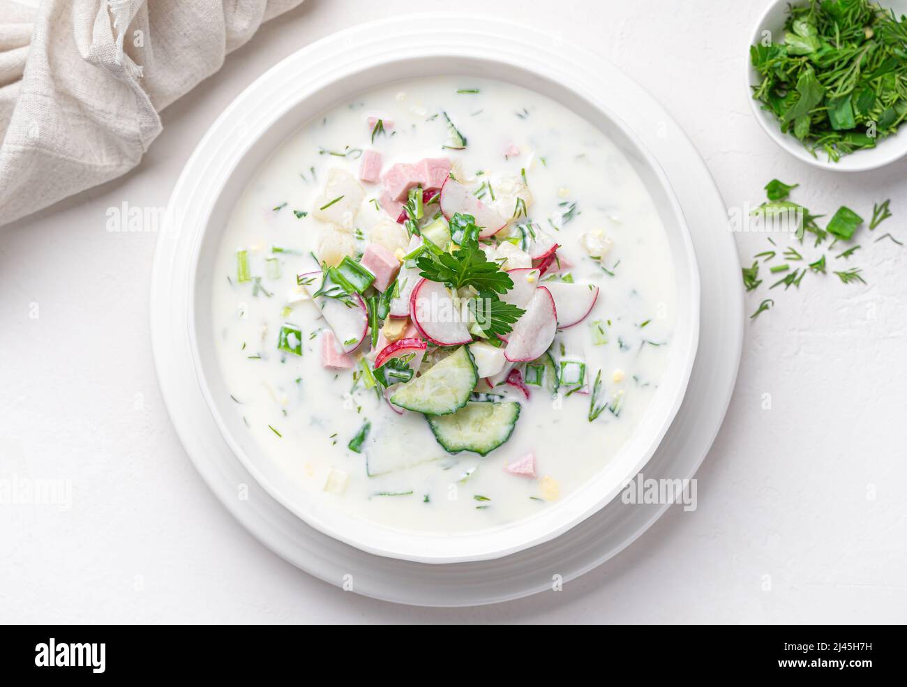 Rinfrescante zuppa di verdure fredde con kefir e salsiccia su sfondo bianco. Vista dall'alto Foto Stock