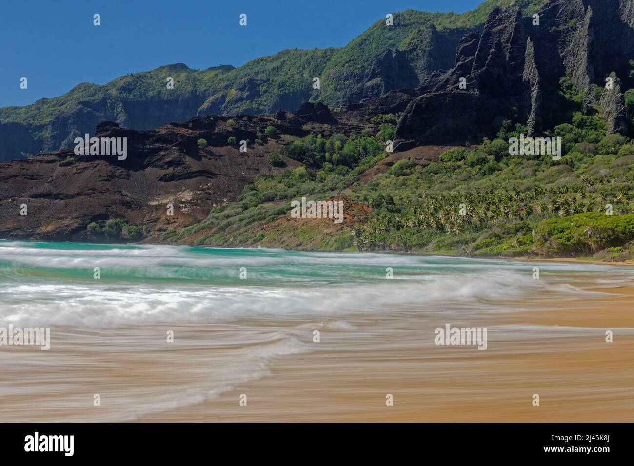 Isole Marquesas, Nuku Hiva: spiaggia nella baia di Haatuatua fiancheggiata da scogliere Foto Stock