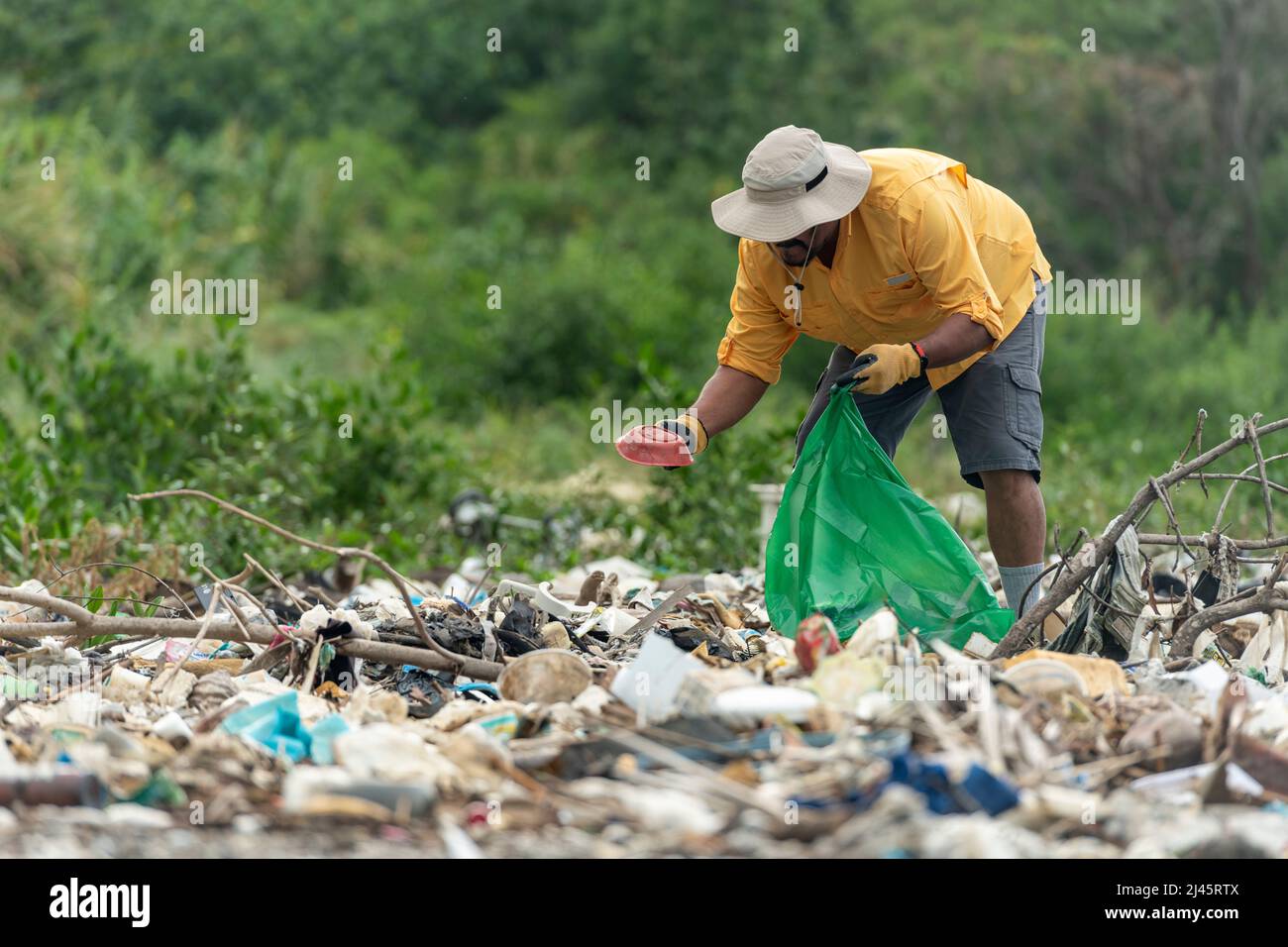 L'uomo raccoglie i rifiuti di plastica sulla spiaggia al mattino, Panama, America Centrale. Foto Stock