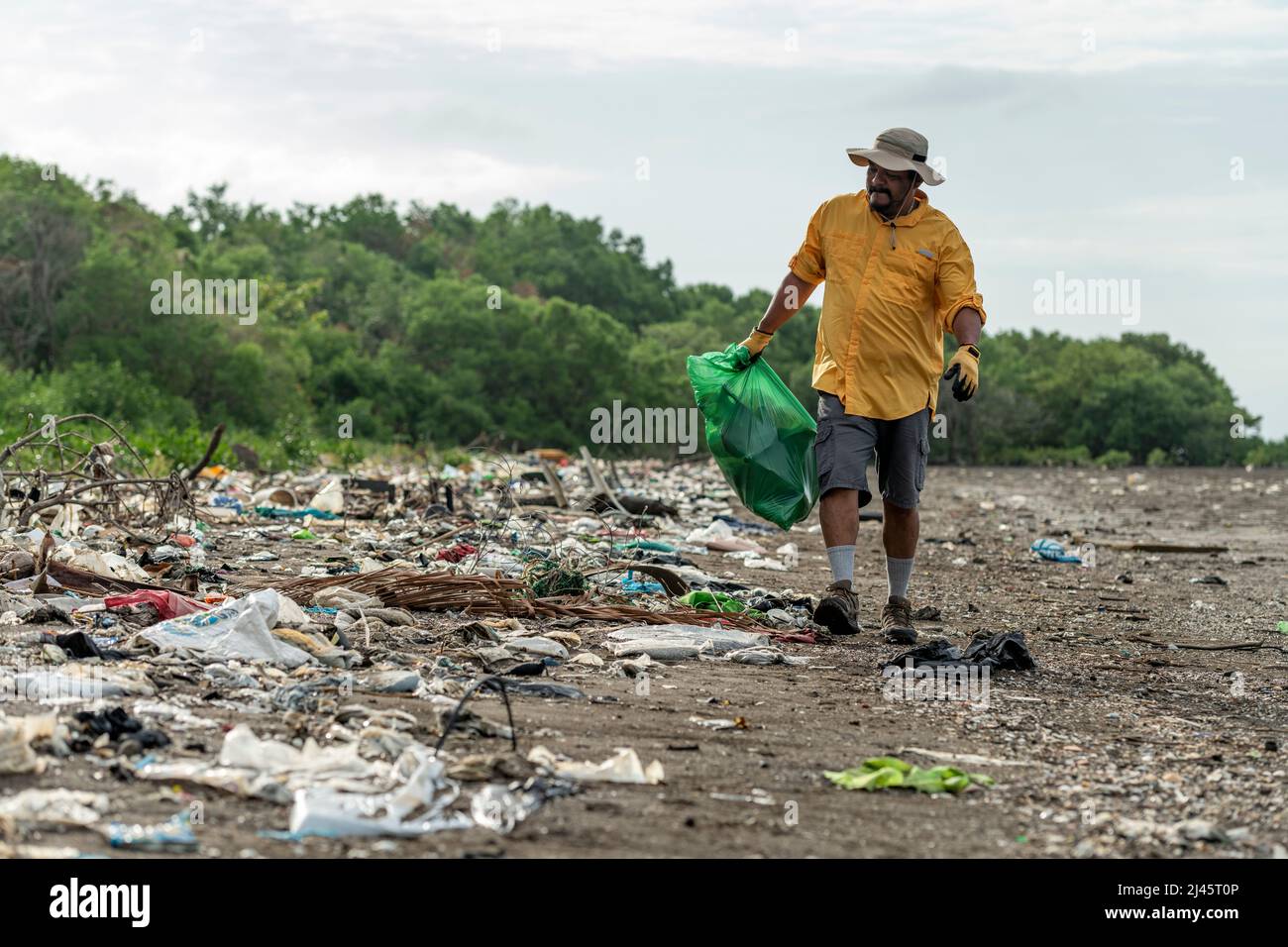 L'uomo raccoglie i rifiuti di plastica sulla spiaggia al mattino, Panama, America Centrale. Foto Stock