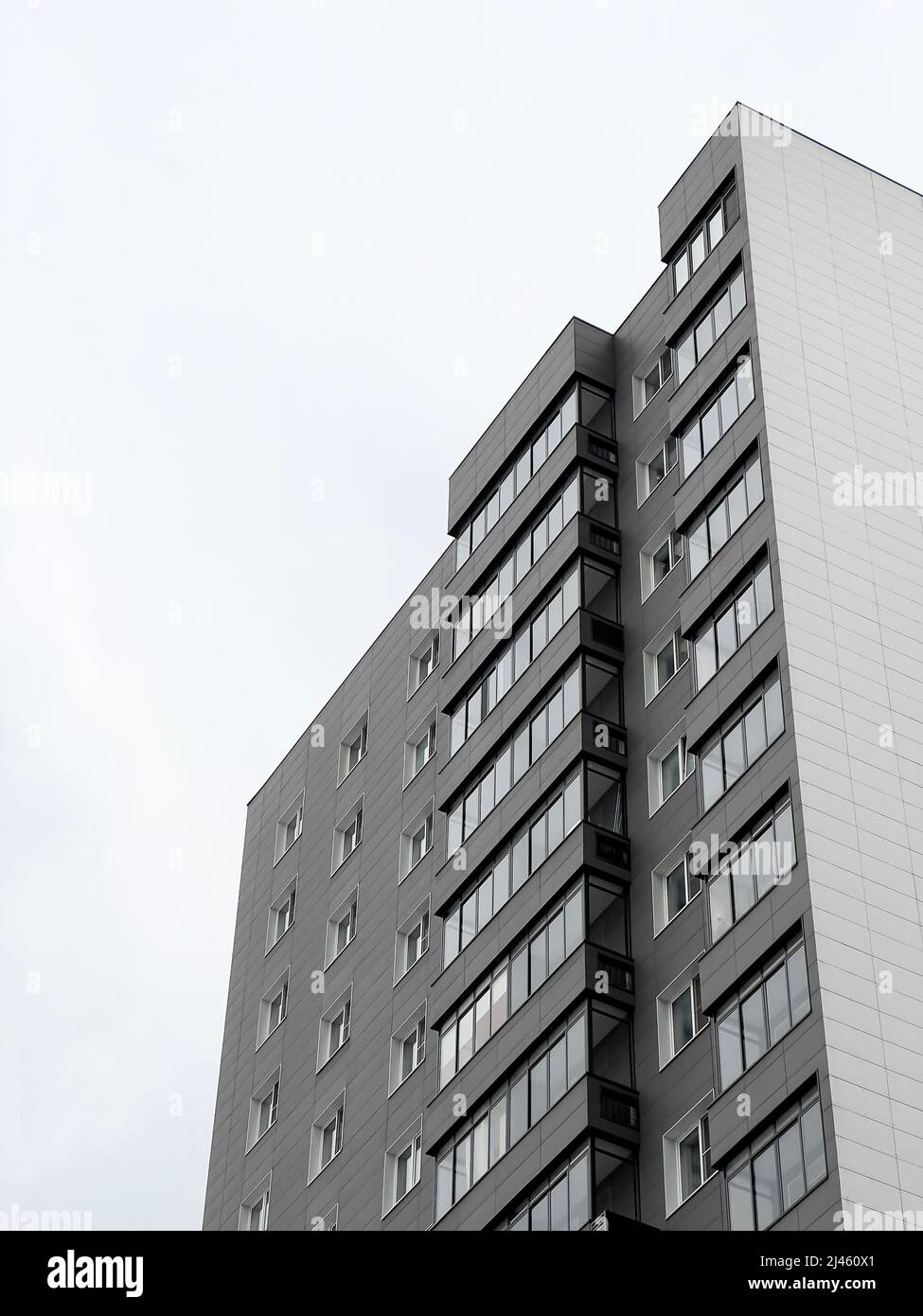 Vista ad angolo basso dal basso del nuovo edificio di appartamenti grigio a più piani che è stato spostato da molte persone attraverso il programma di ristrutturazione Foto Stock