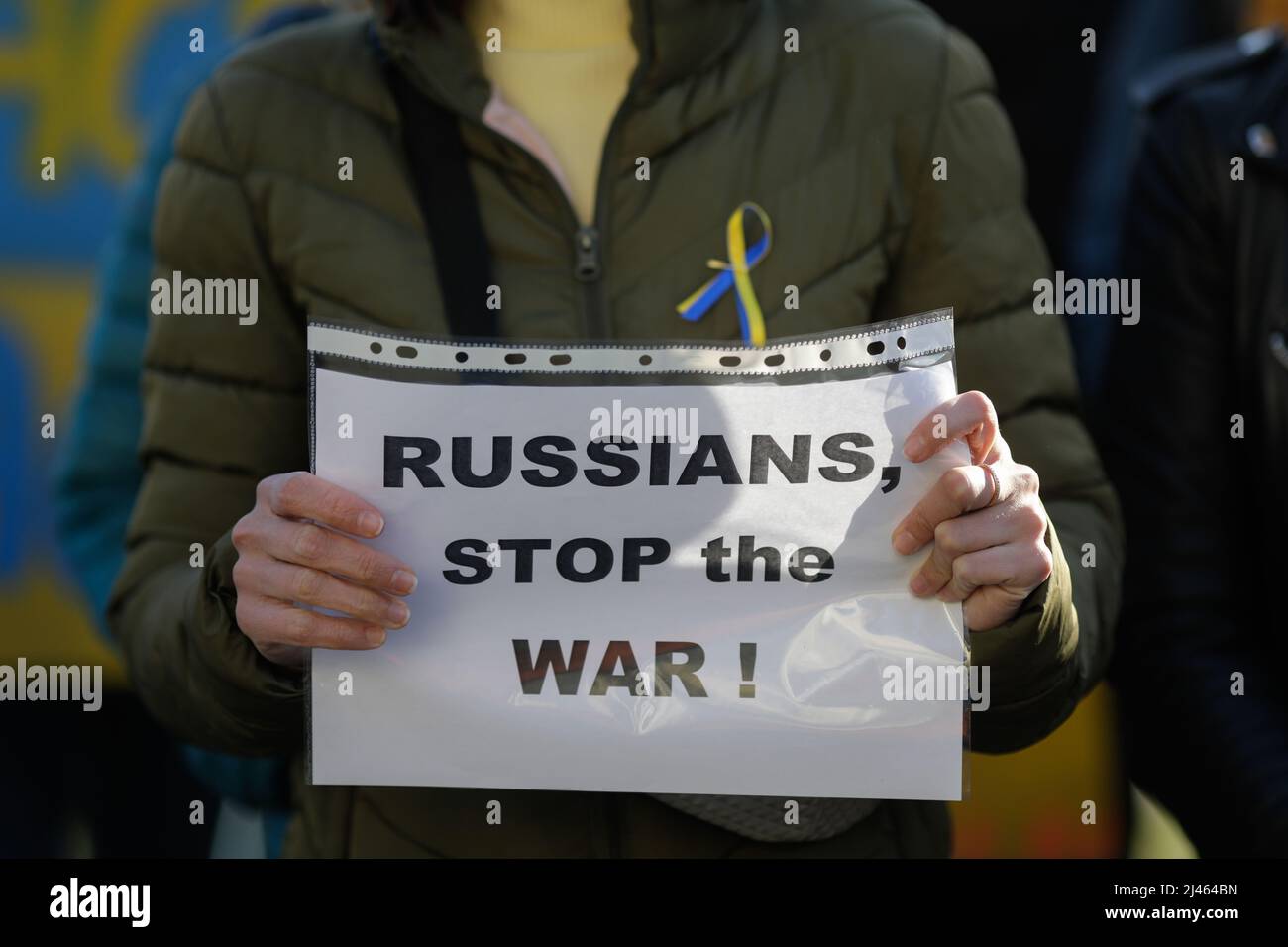 Dettagli con le mani di una donna Ucraina in possesso di una bandiera anti-guerra, pro Ucraina e anti Russia durante una protesta anti-guerra a Bucarest, Romania. Foto Stock