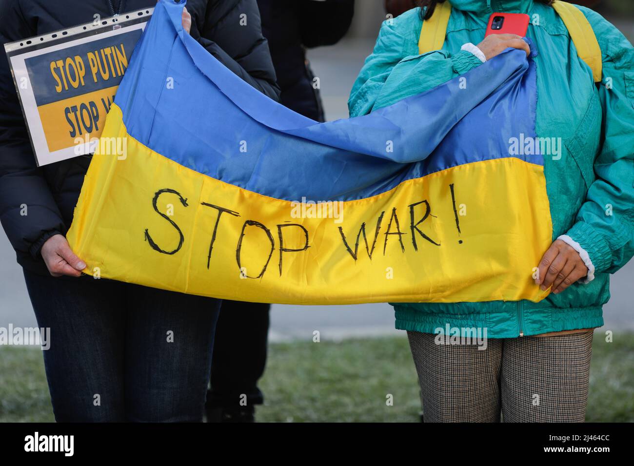 Dettagli con le mani di una donna Ucraina in possesso di una bandiera anti-guerra, pro Ucraina e anti Russia durante una protesta anti-guerra a Bucarest, Romania. Foto Stock