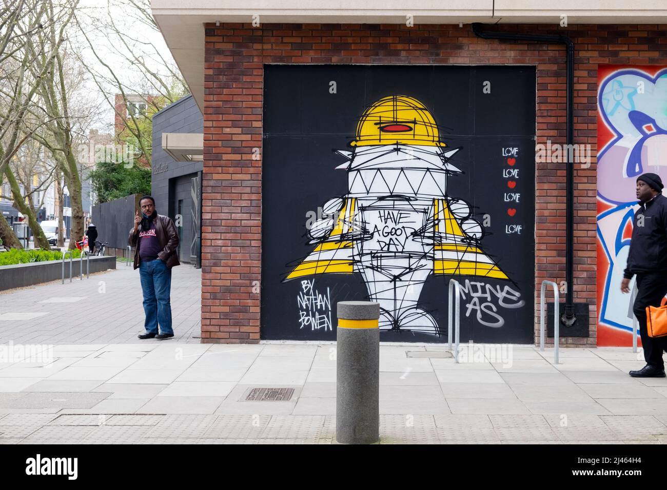 Pedone, uomo, persona, persone che camminano accanto graffiti murali opere d'arte su un muro in Old Street Shoreditch Londra EC1 Inghilterra Regno Unito KATHY DEWITT Foto Stock