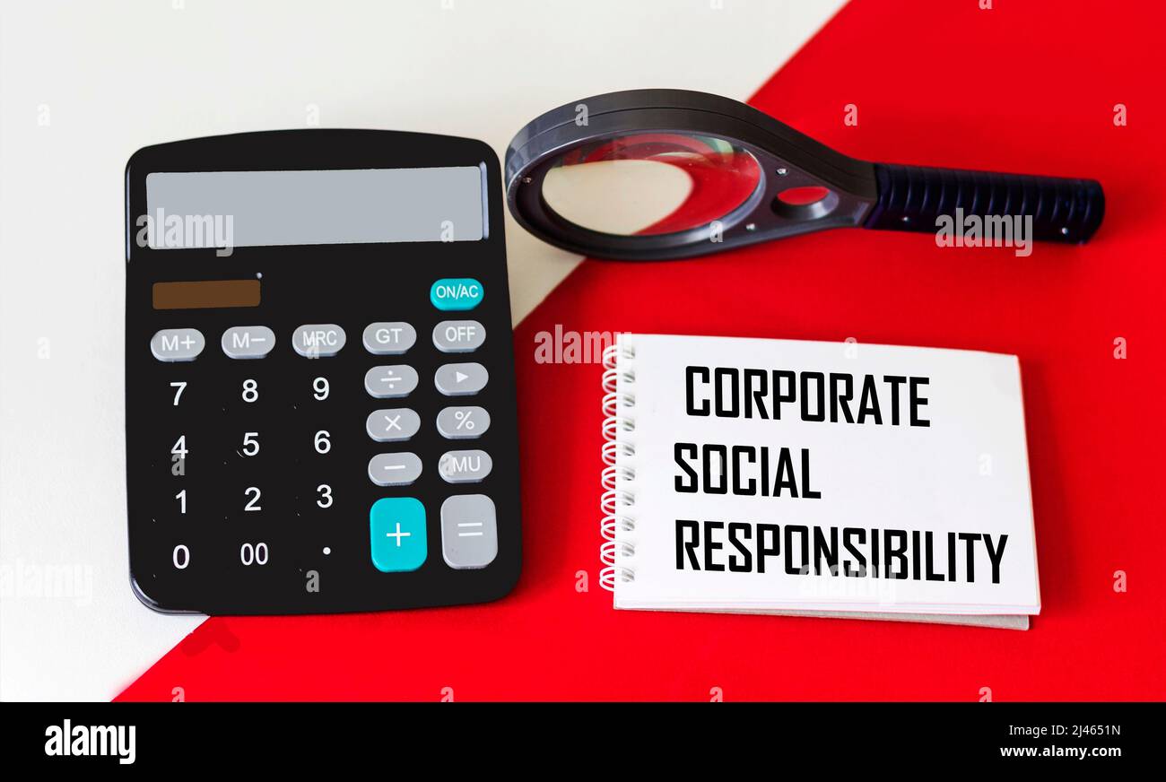 CSR concetto di responsabilità sociale aziendale su un blocco note con una calcolatrice e una lente di ingrandimento su sfondo rosso e bianco Foto Stock