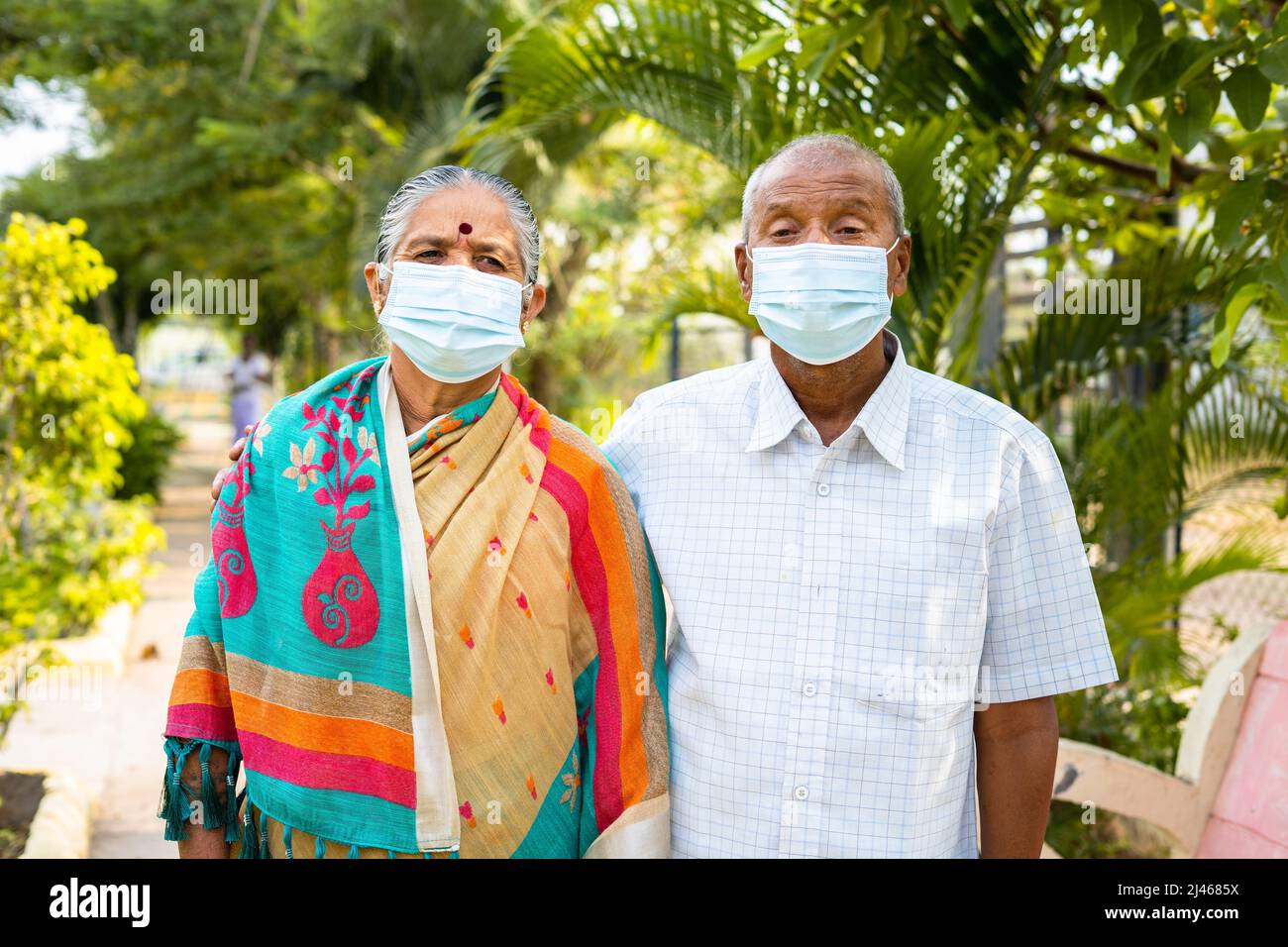 Coppie anziane con maschera medica durante la passeggiata mattutina al parco - concetto di covid-19 protezione del coronavirus, salute e sicurezza. Foto Stock